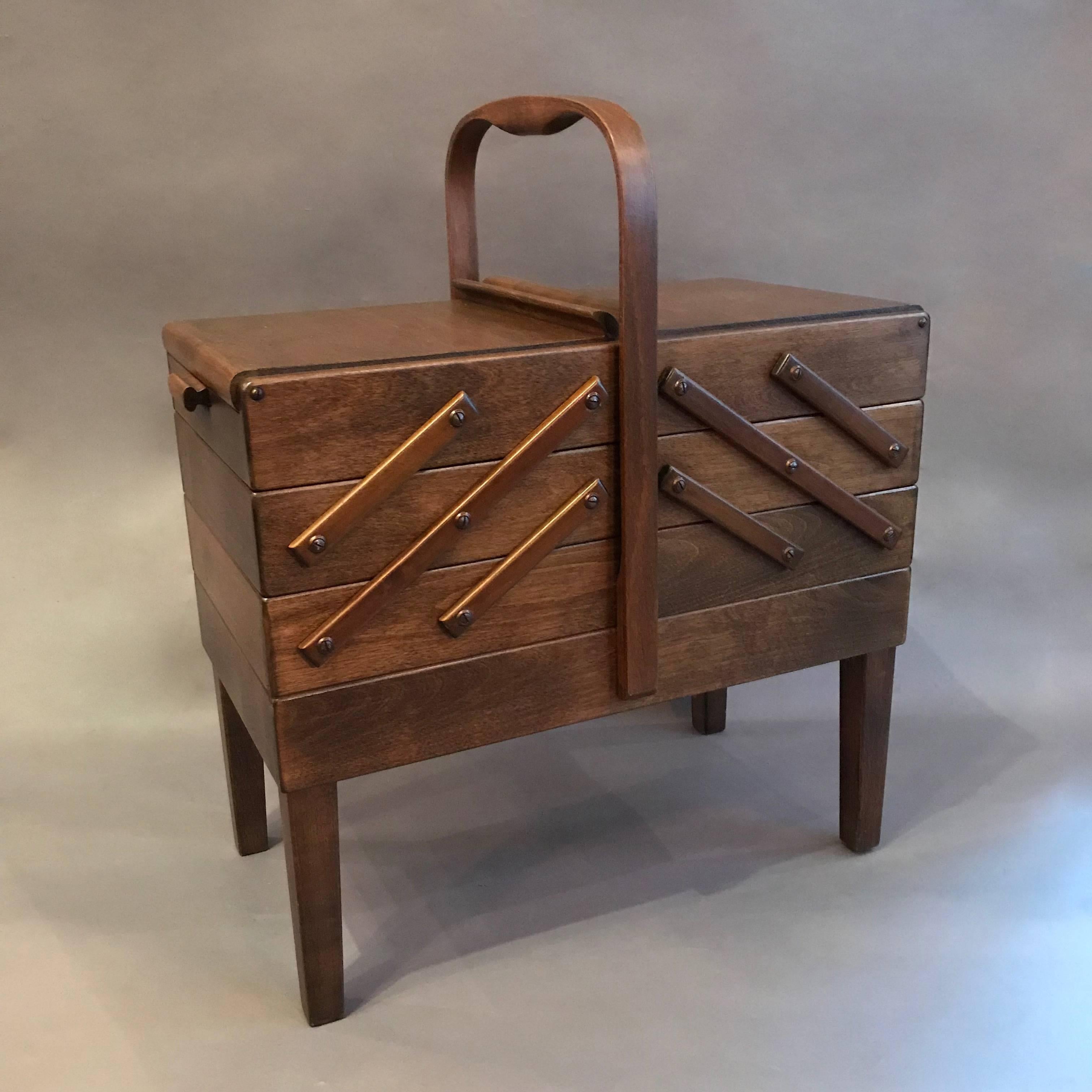 Scandinavian Modern, teak sewing basket features accordion expansion on either side with graduated trays from 21 - 67 in.