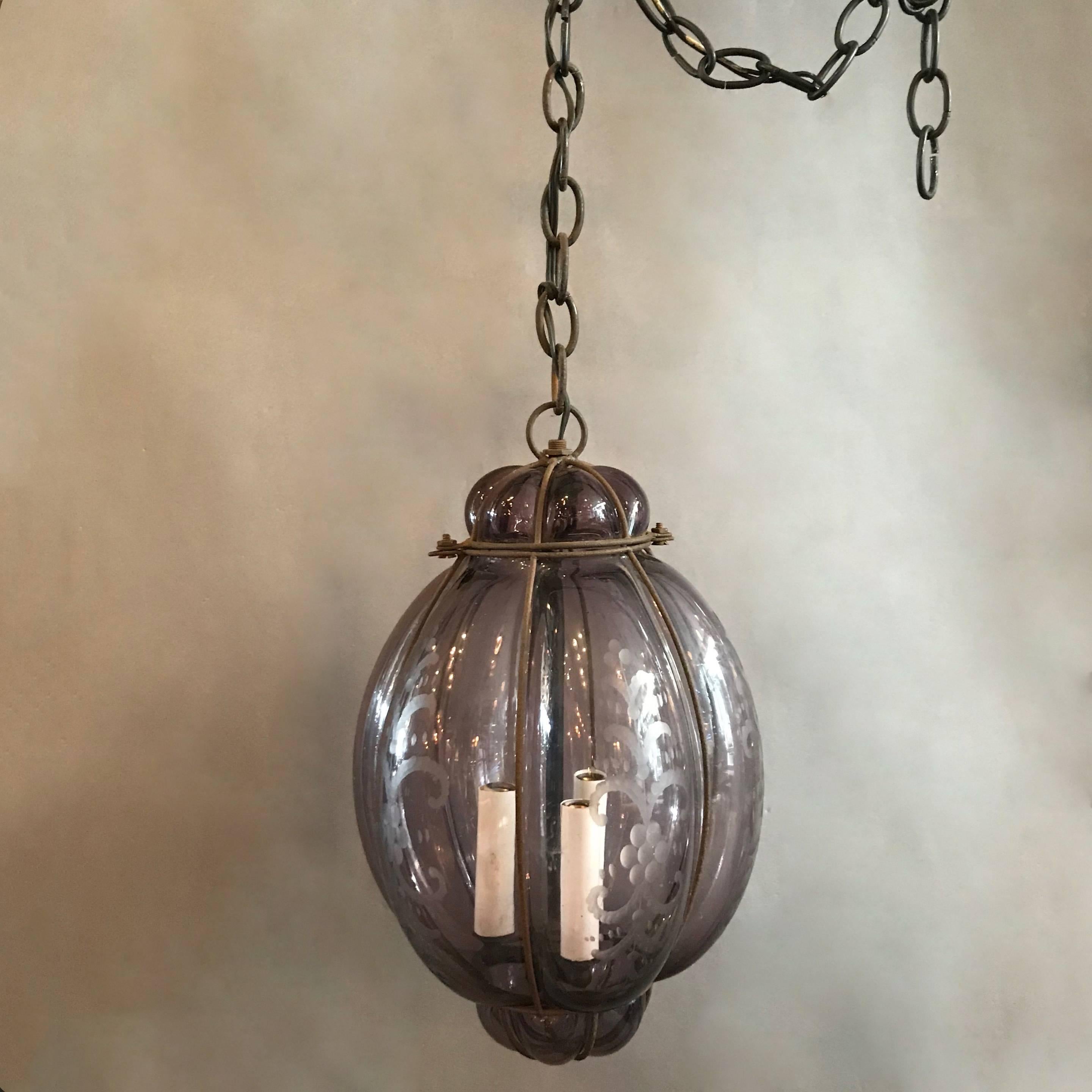 Italian, amethyst colored, Seguso, Murano glass pendant light, handblown within an iron cage features three candelabra bulbs that can accept 40 watt bulbs each on 24 in of chain.
