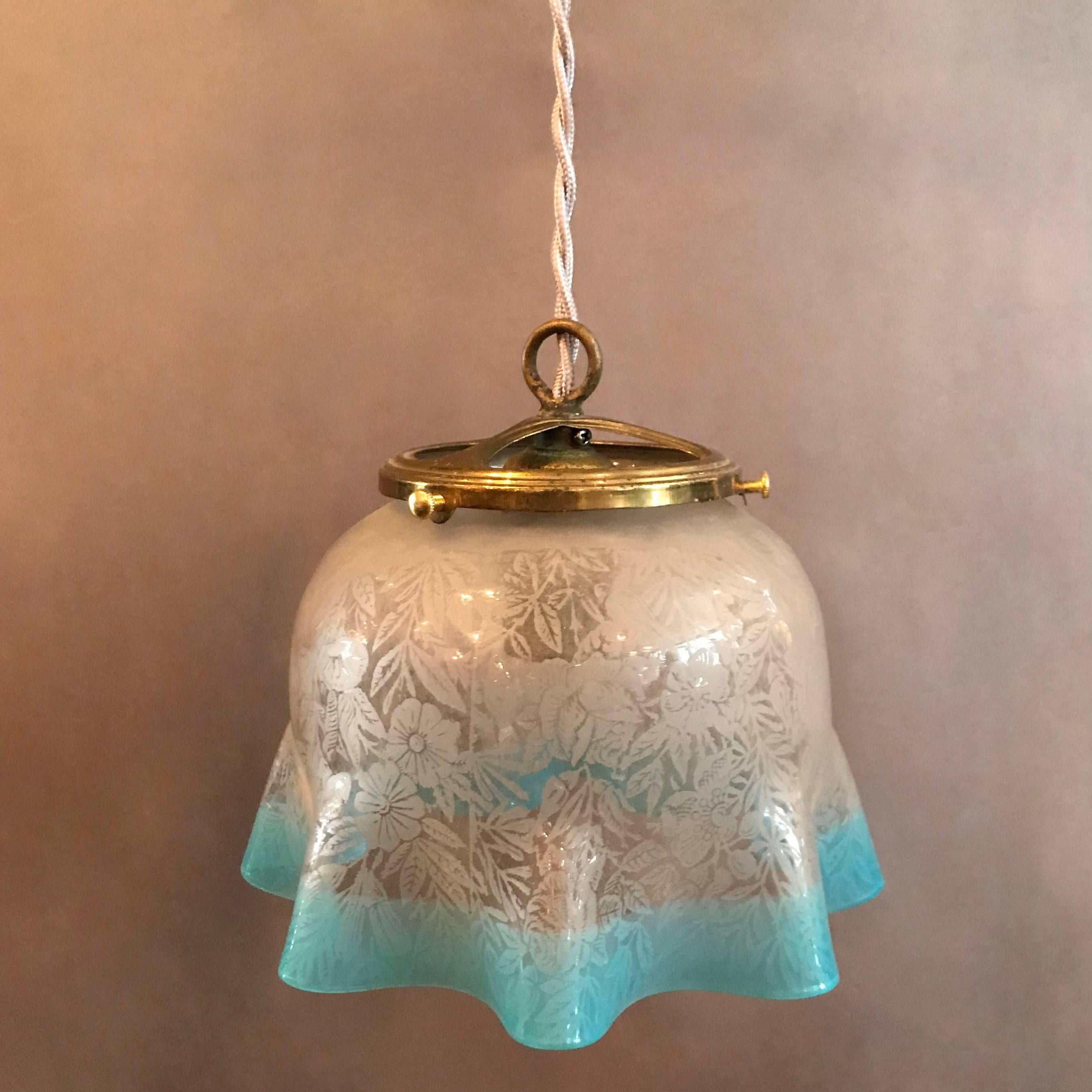 Antique, late 19th century, pendant features a ruffled, intricately etched, foliate pattern glass shade with light blue trim and open brass fitter. This light is newly wired for up to a 100 watt bulb with 48in. of braided cloth cord.