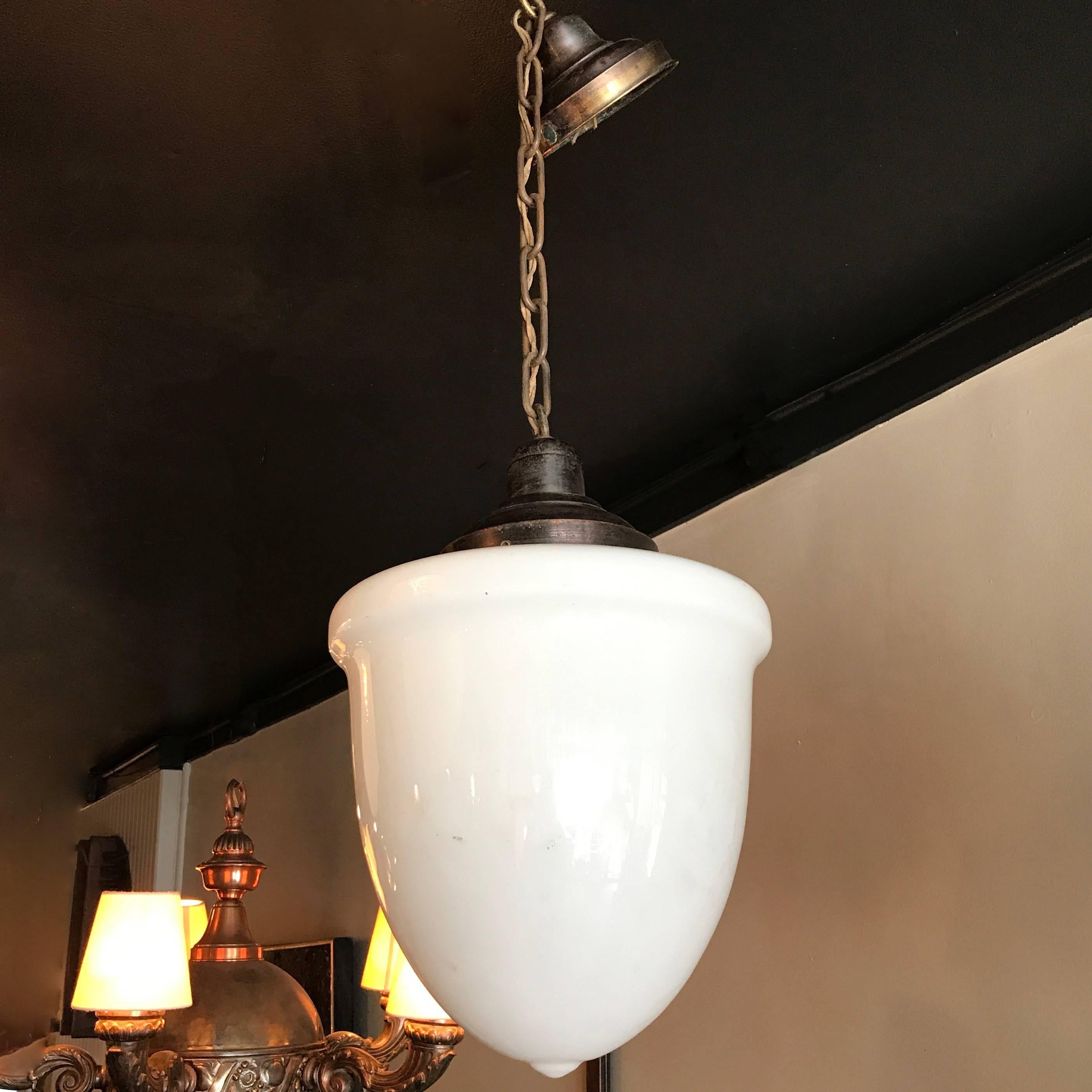 Art Deco, pharmacy pendant light features an elongated milk glass shade with brass fitter, 24 inches of chain and canopy is newly wired and can accept up to a 200 watt bulb.