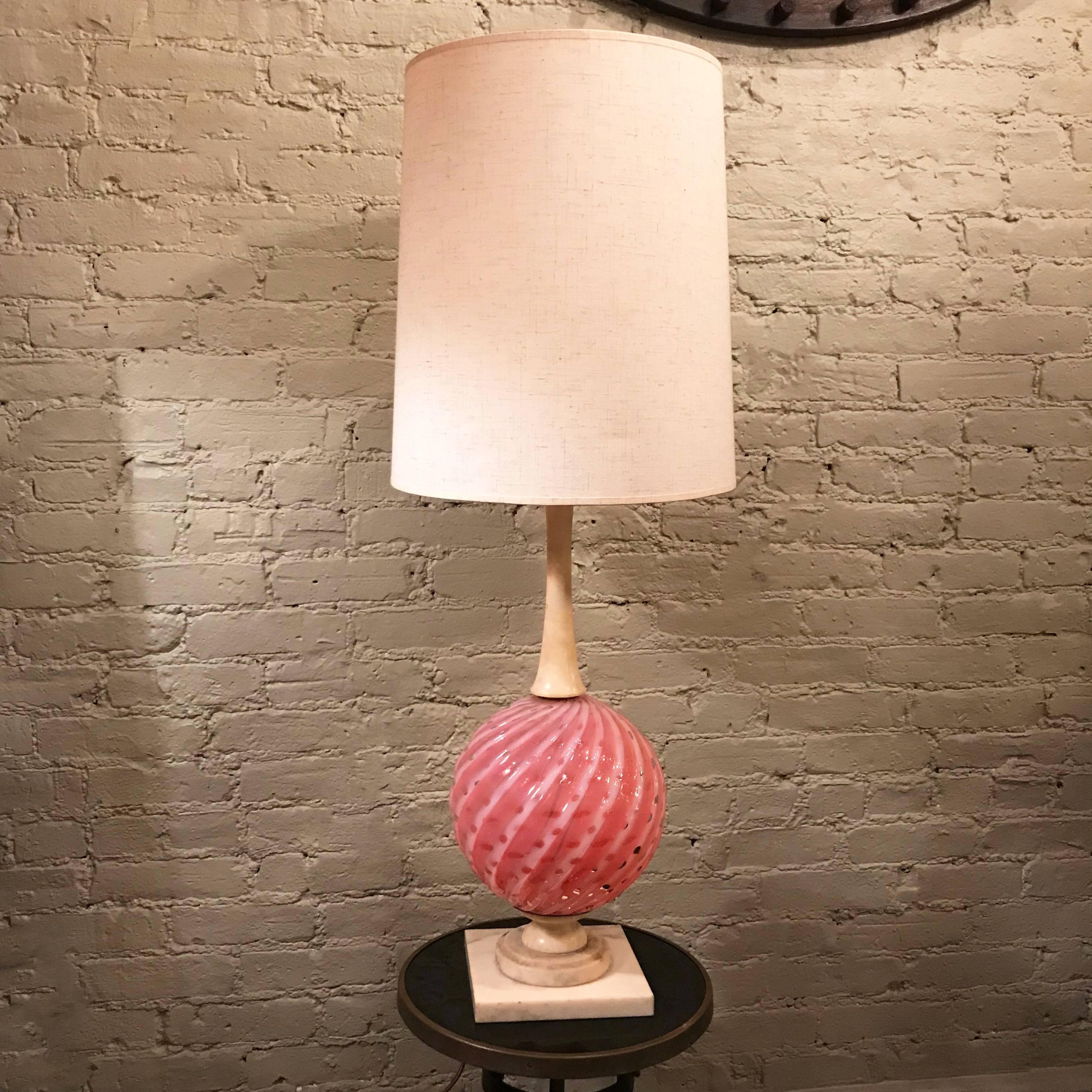 Italian, midcentury, Hollywood Regency table lamp features a pink, swirled Murano glass globe between a sculpted marble base and stem with brass harp and finial. The lamp features three-way illumination alternating from top to bottom and altogether.