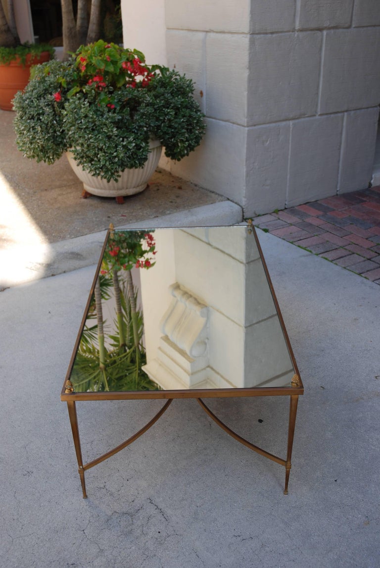 Coffee table
Clear mirror top
Metal legs
Metal crossing entretoise
Pineapple finials at four corners of mirror.
Very gracious design.