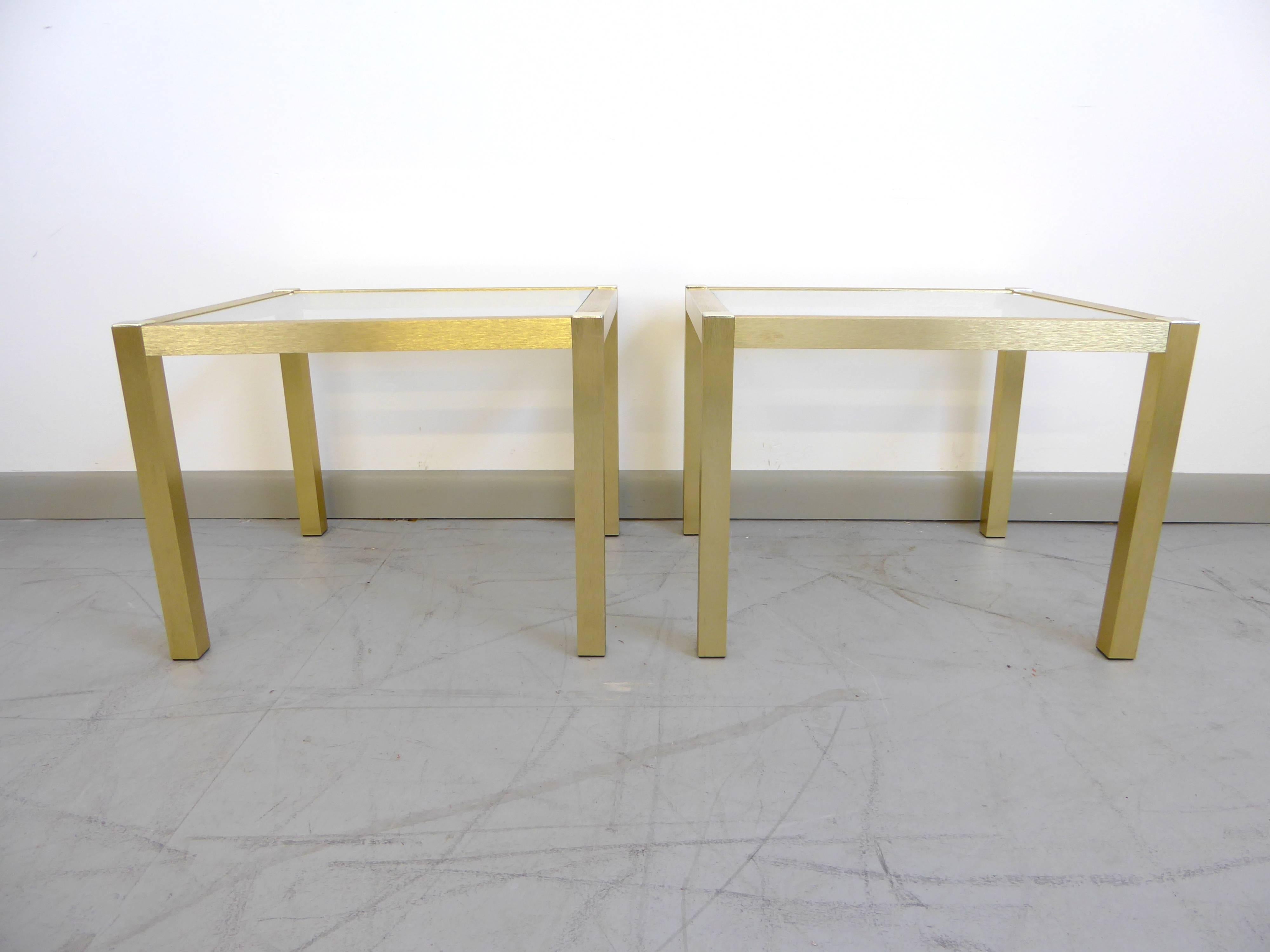 Glamorous pair of brushed brass end tables with original glass tops. Brass has a wonderful shimmer effect. Beautiful and stylish pair of vintage tables.

  