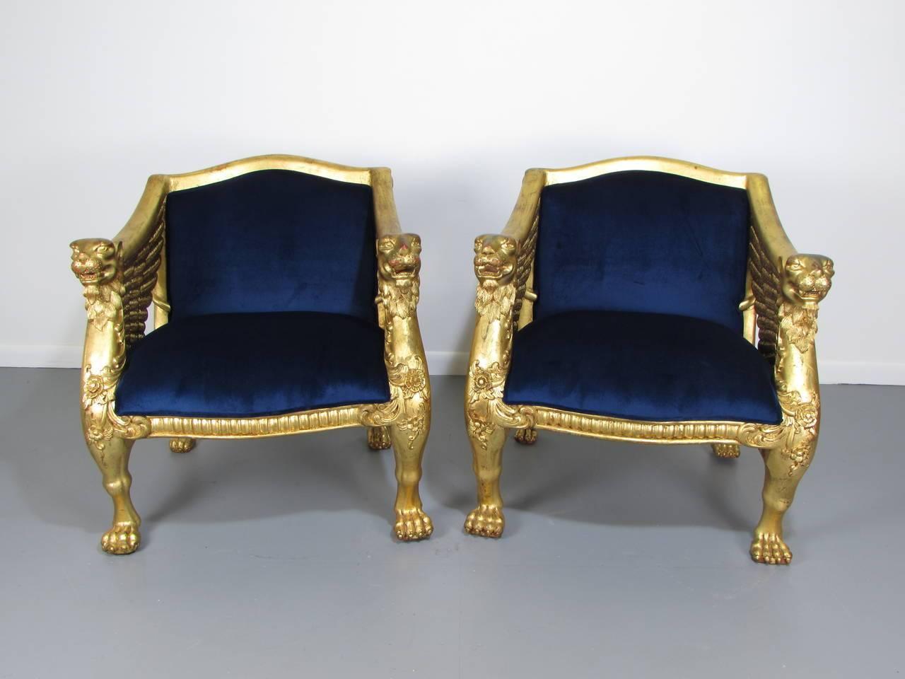 Luxurious and exceptional pair of 19th century French Empire hand-carved winged giltwood bergeres. Incredible detail and workmanship. Newly upholstered in a deep royal blue velvet. Age wear.