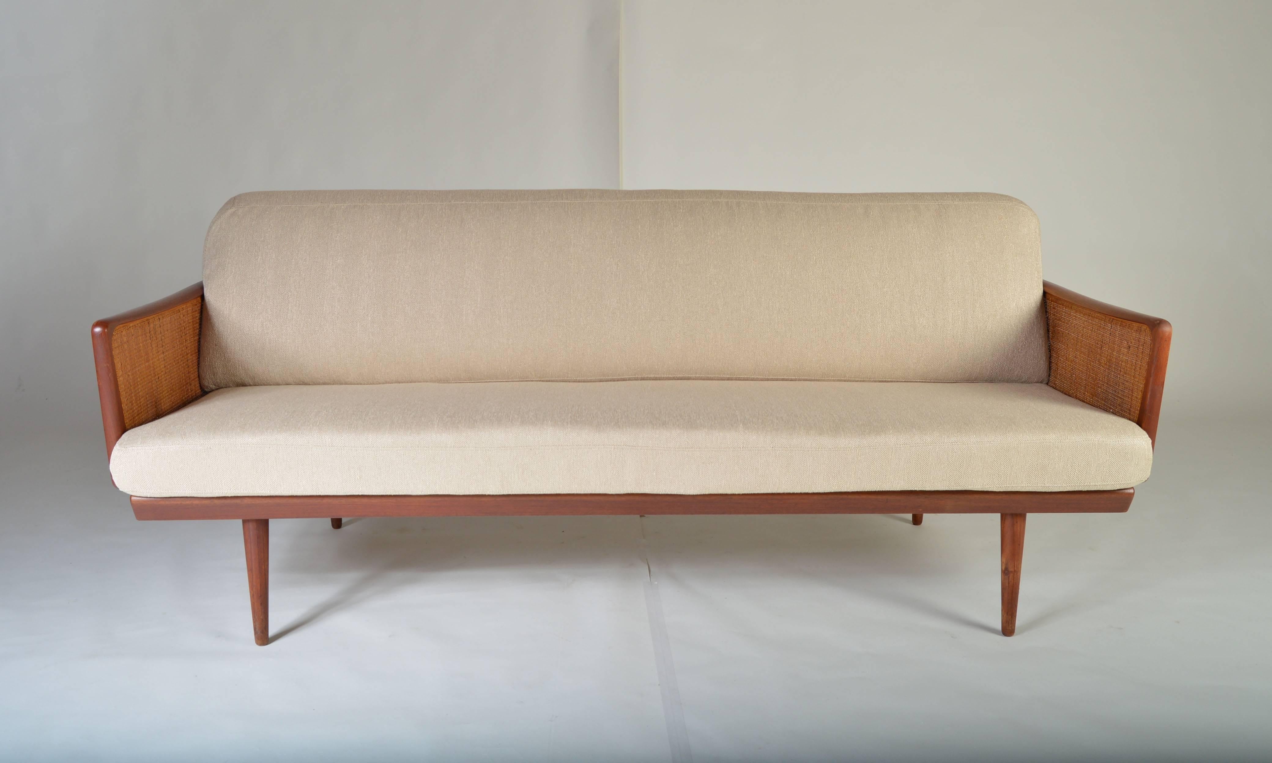A full length sofa framed in teak and cane designed by Peter Hvidt.