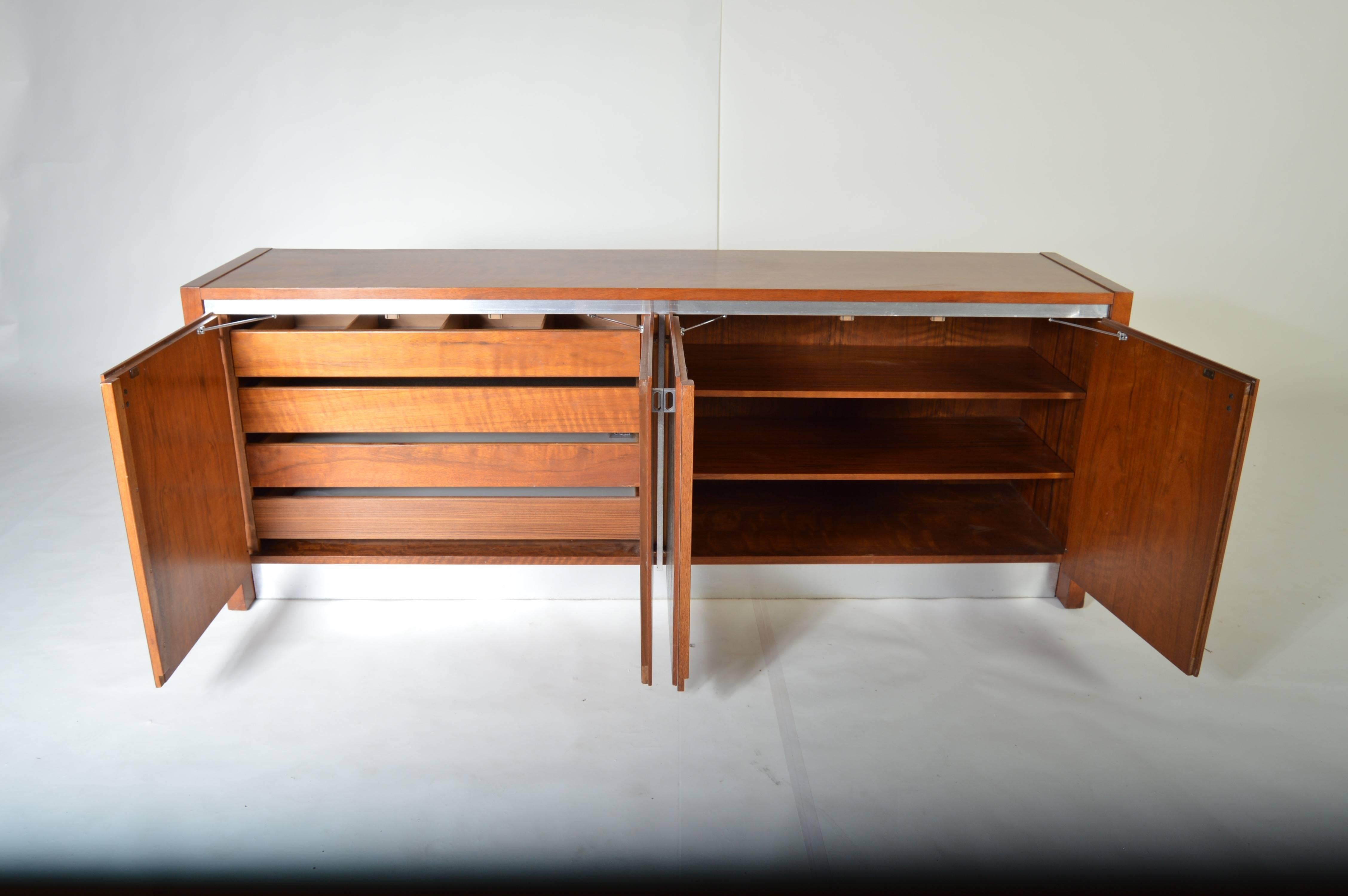 A walnut sideboard attributed to Milo Baughman by Founders having aluminum trim throughout the front and spring resisted doors. Ample storage space.
