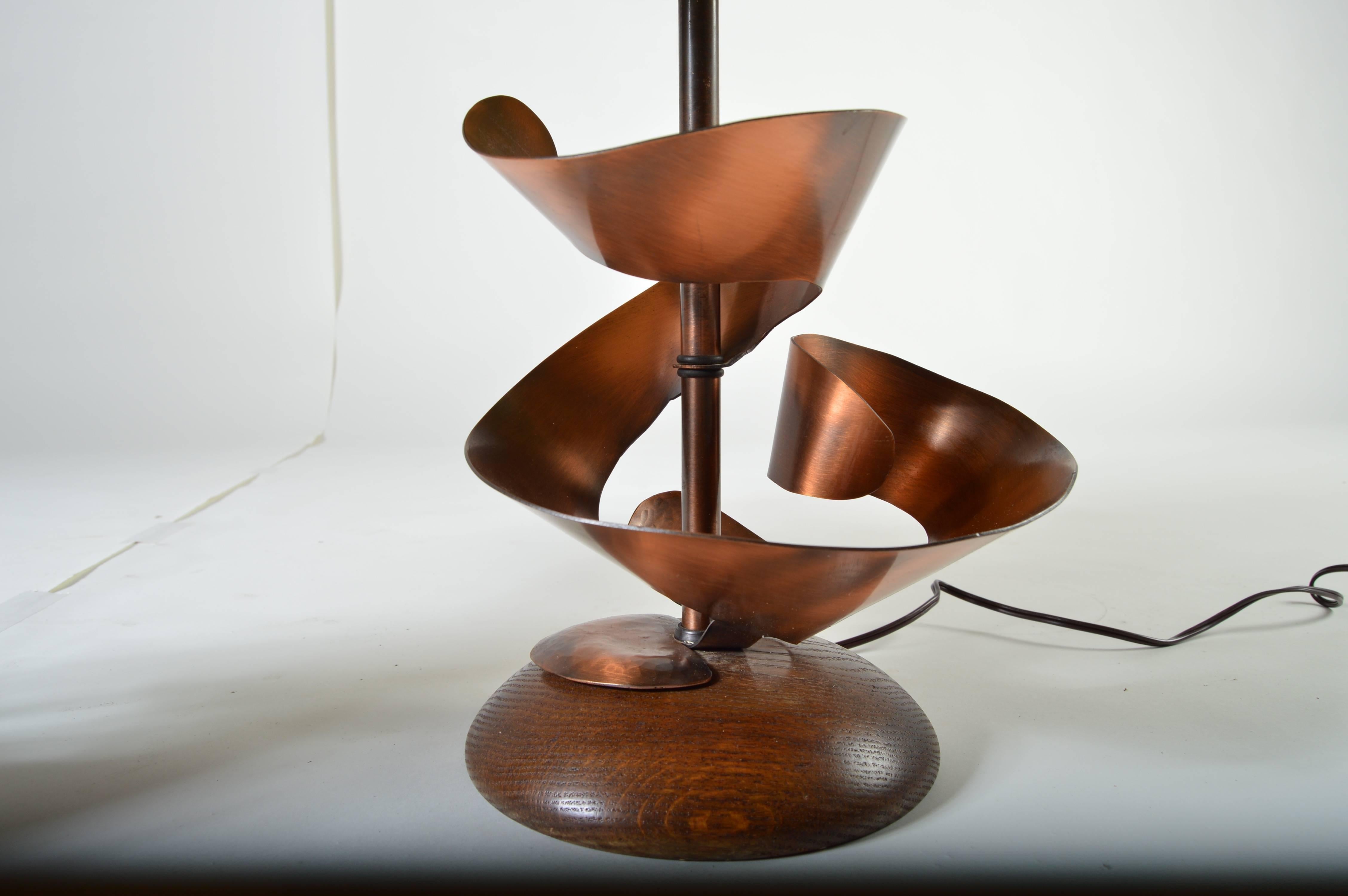 A pair of sculptural copper table lamps designed by Harry Balmer having original shades and wooden caps.
