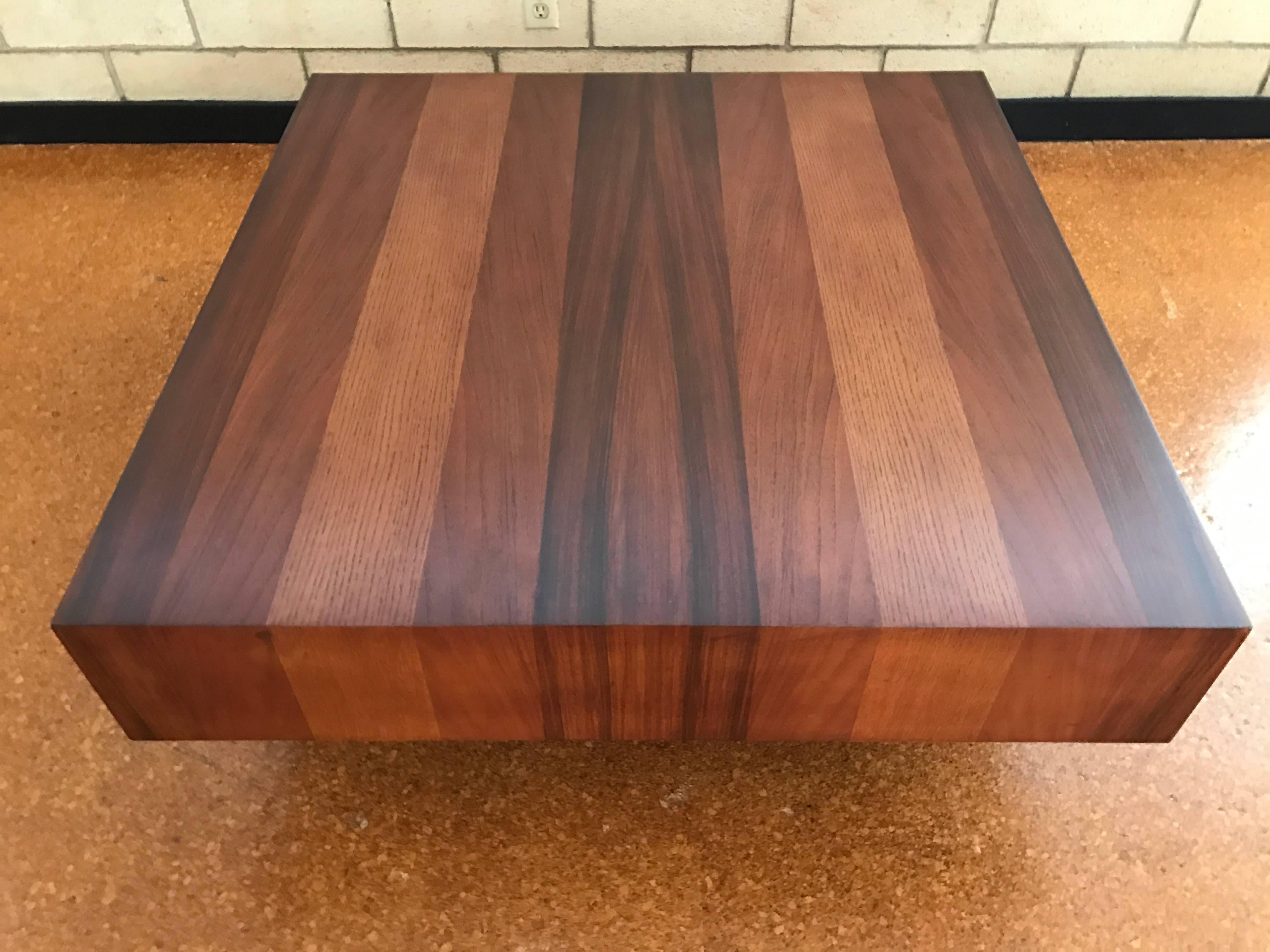 Rosewood, walnut and oak mixed woods coffee table on a black plinth base by Dyrlund, Denmark. Measures: 41" square x 18" tall. Refinsihed.