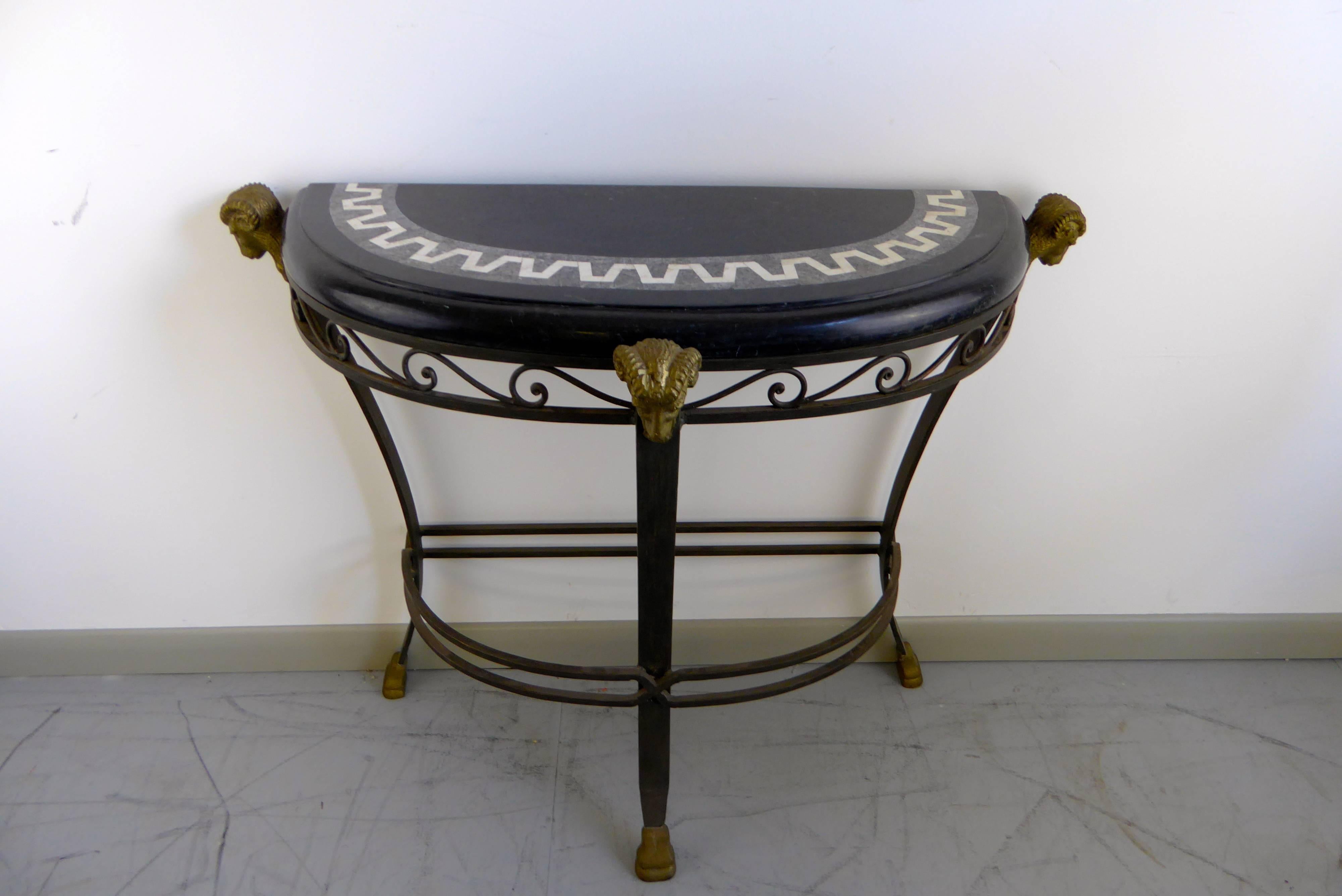 Stunning vintage demilune iron console table featuring a tessellated marble top and bronze ram's head accents attributed to Maitland Smith.