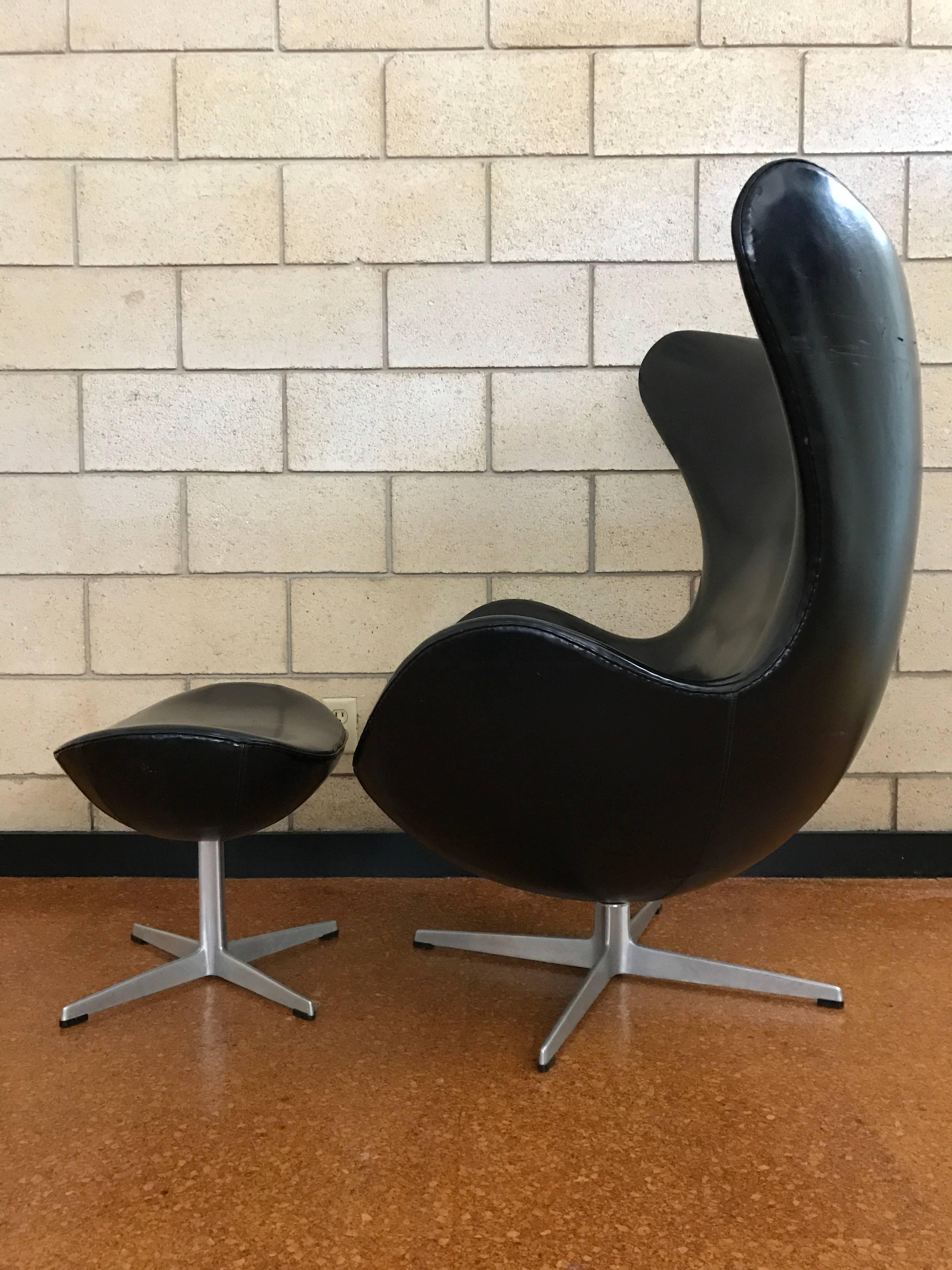 A rare, early example of Arne Jacobsen's classic Egg chair with original ottoman. There were a few runs in vinyl in the first years of production. This is one of them. 
 The signature of these earliest examples is located underneath the vinyl on