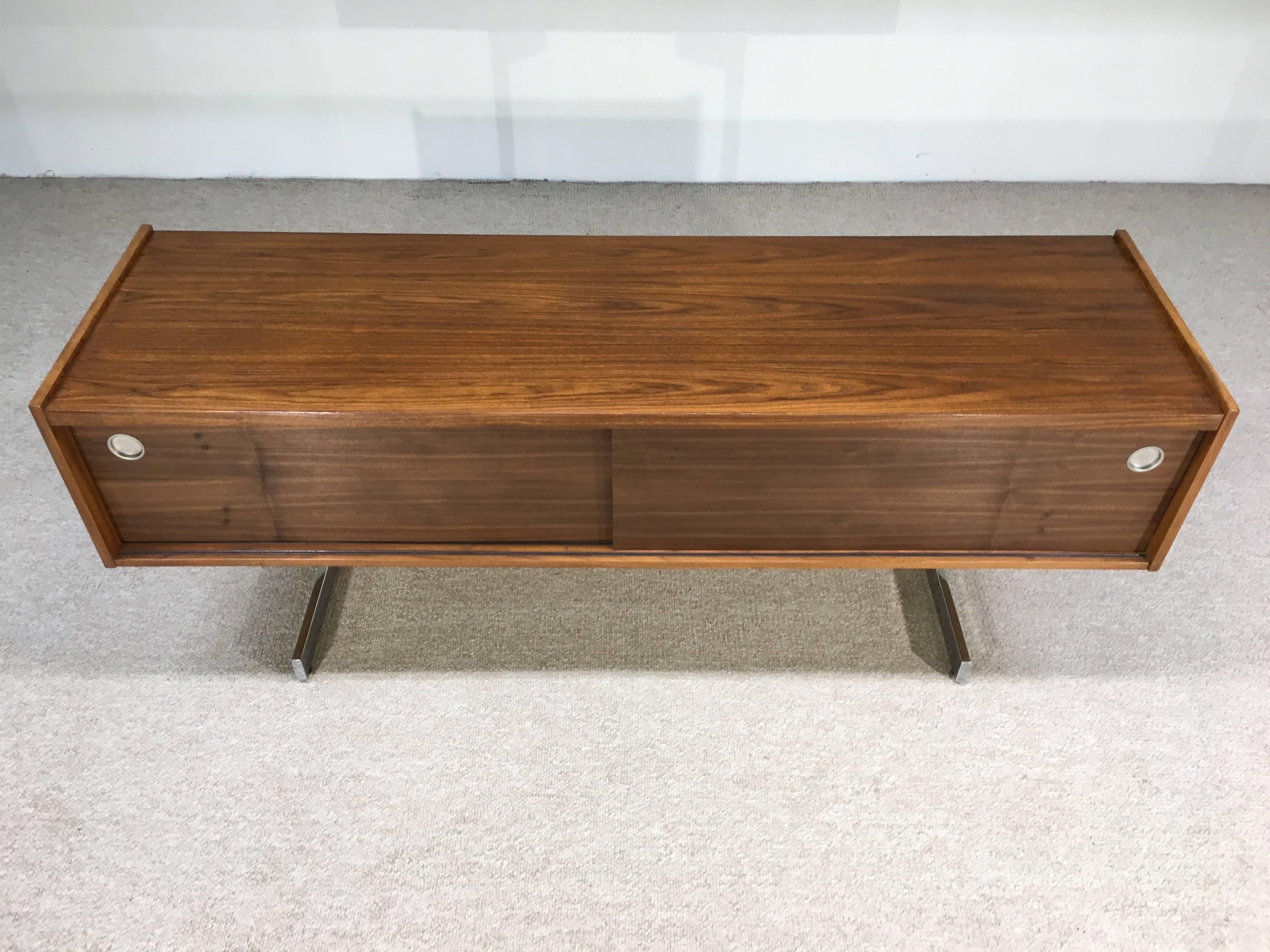 A very attractive and rare cantilever credenza by Opus having walnut cabinet and interior that stands on chrome cantilever legs. Ample storage including three drawers, cabinet space and a file drawer.