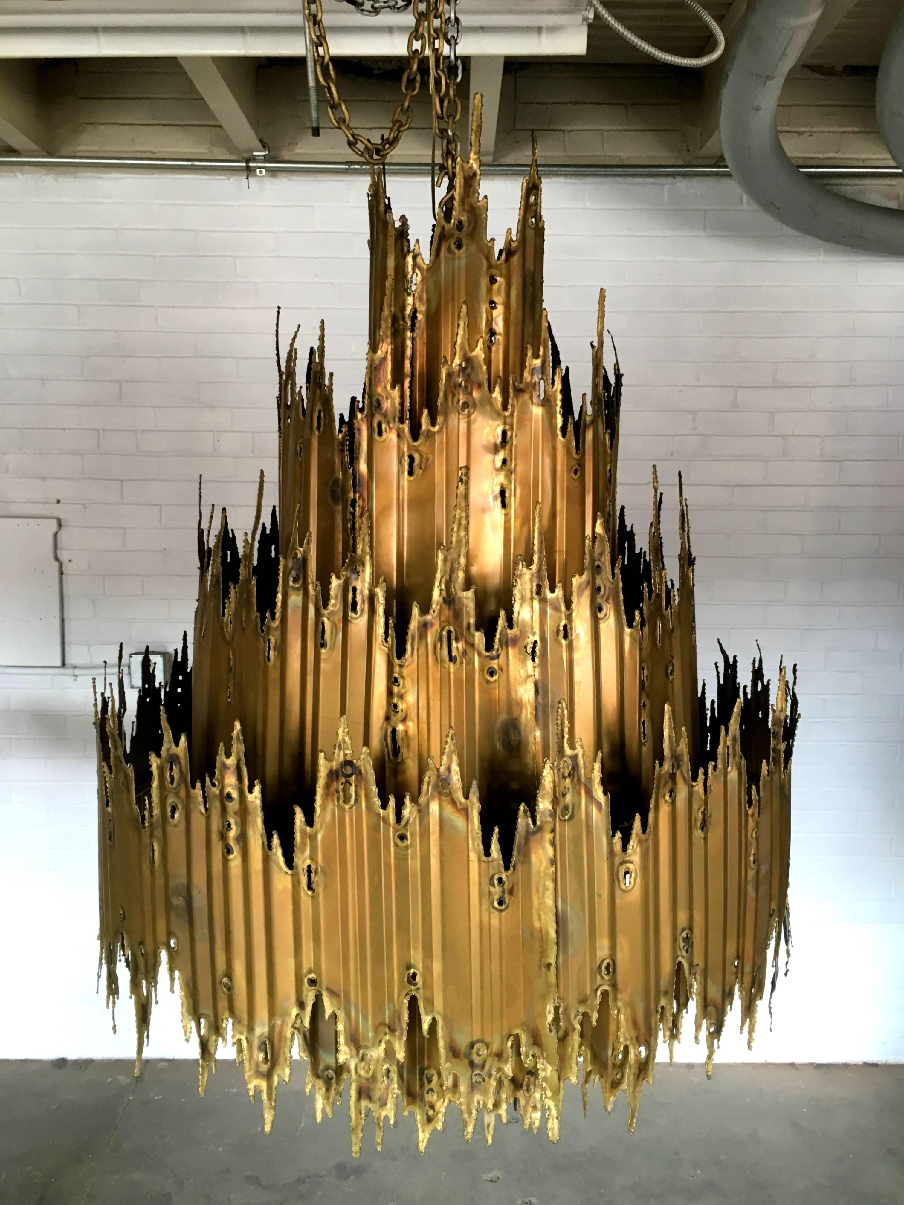 Monumental and massive torch cut brutalist chandelier by Tom Greene for Feldman Lighting.
This is the largest model ever produced at a whopping 60" from top to bottom. And 40" across!
Incredible condition!