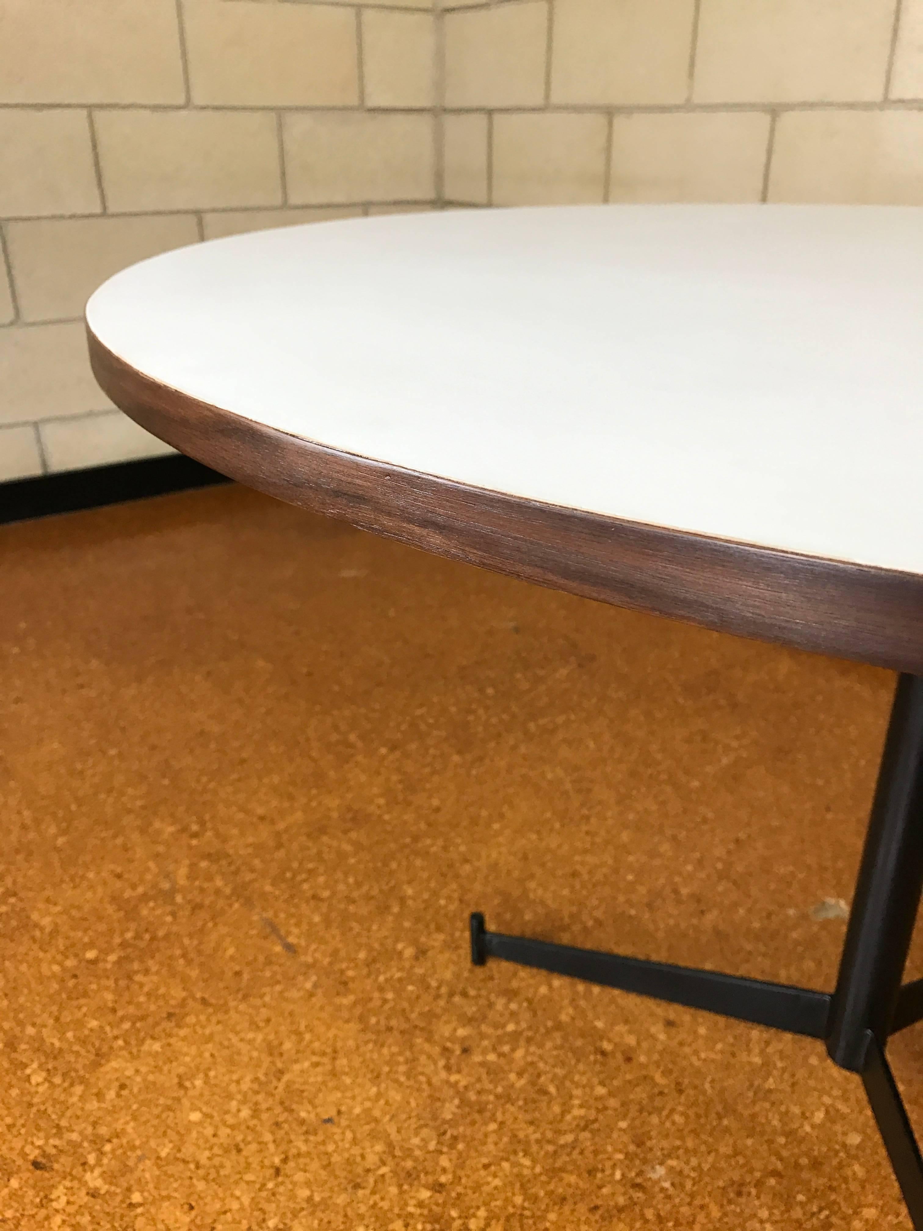 Restored Paul McCobb style round dinette dining table made of an iron three star iron base and white Formica top with walnut trim. The white Formica top, walnut trim, and iron bade have been restored. The top detaches from the base with a