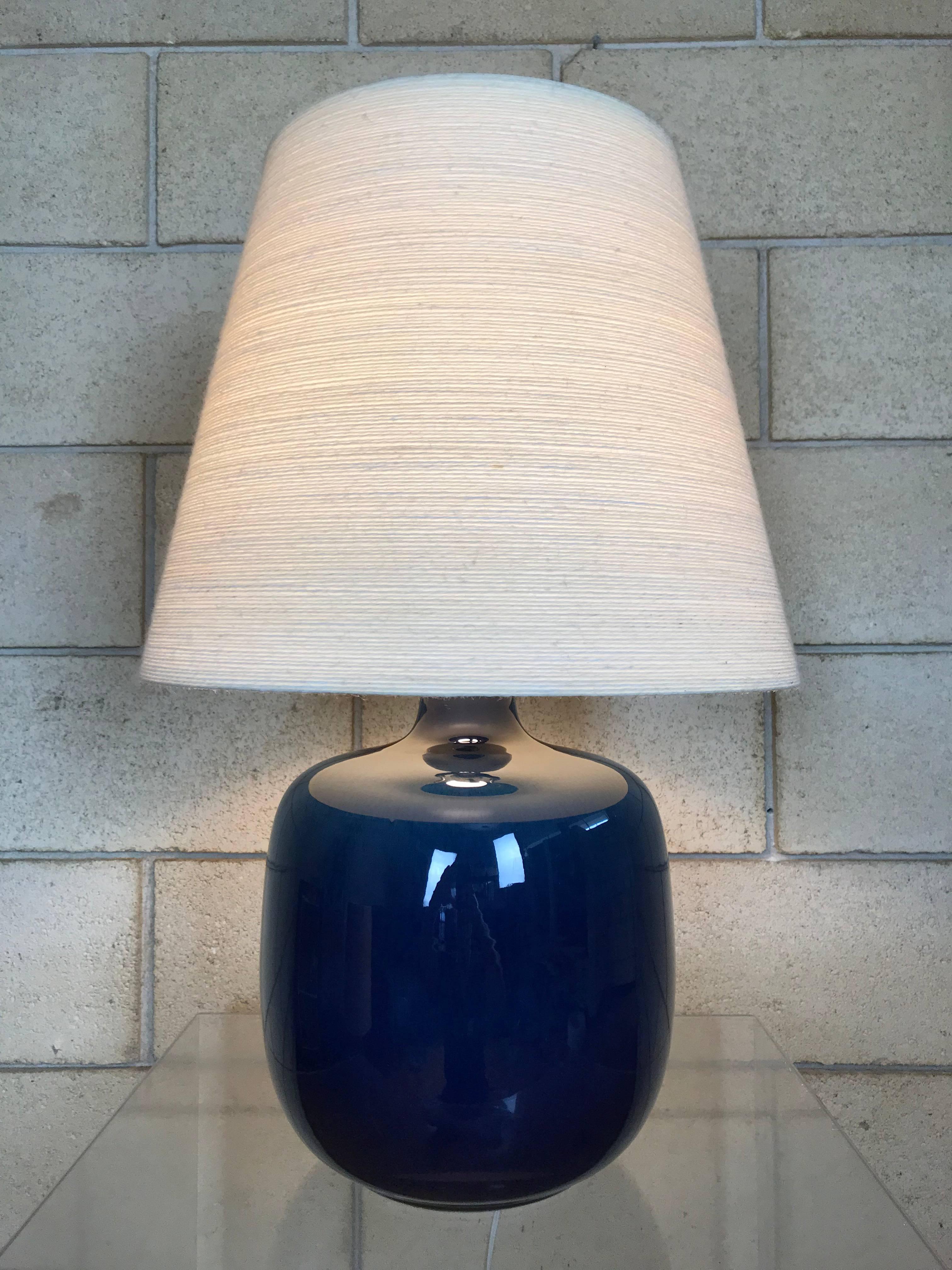 Beautiful and pristine royal blue ceramic table lamp by Lotte & Gunnar Bostlund, Sweden; 1960s. Original fiberglass/string jute shade.  Any imperfections in the images are reflections from the studio lighting. This lamp is in excellent vintage