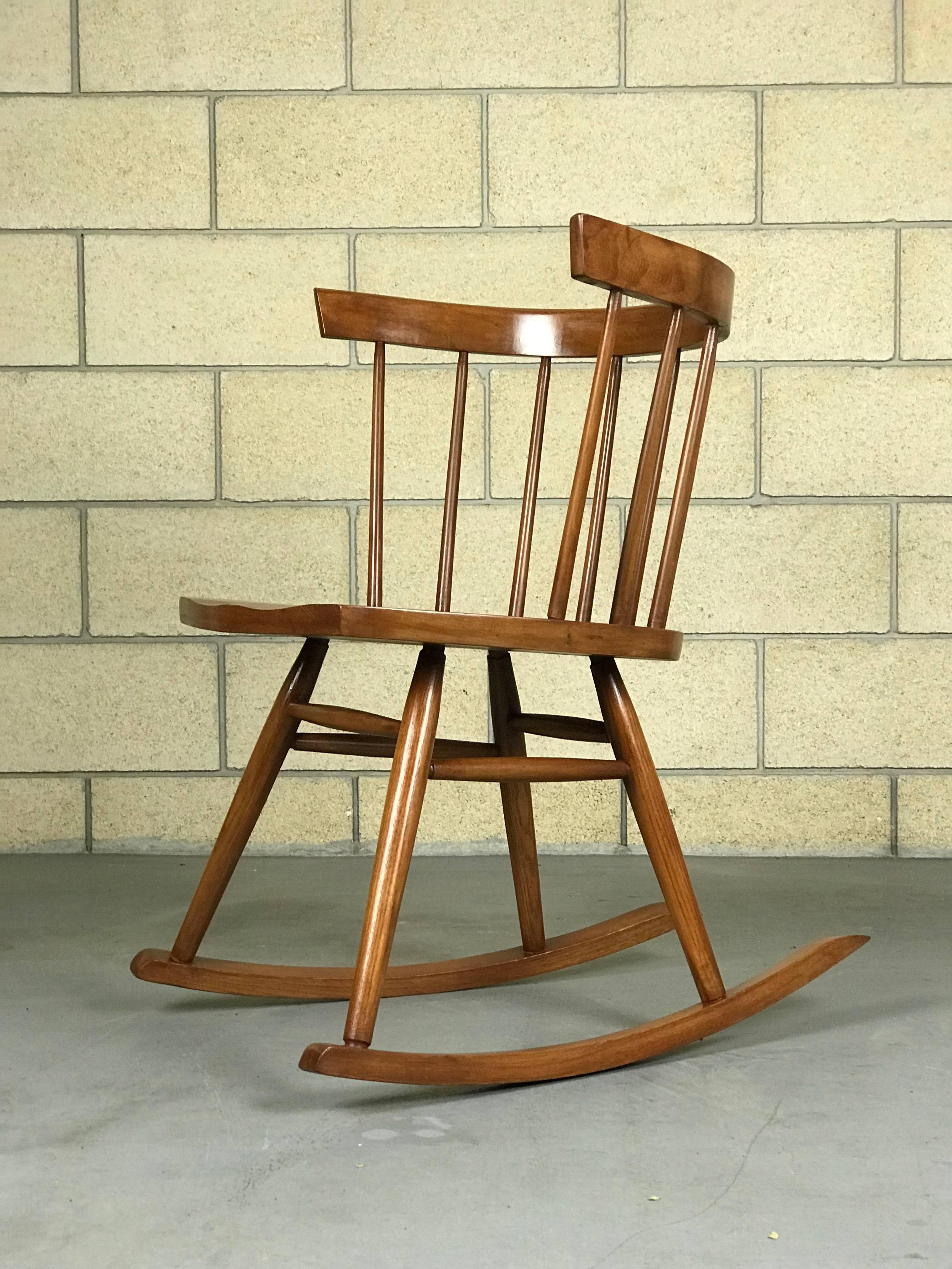 Minimalist windsor style rocker by Ercol Furniture of England; refinished, circa 1950s. This has been used since refinishing and shows some very minor wear. Studio lighting brightens the color. It's a walnut stain and satin finish.