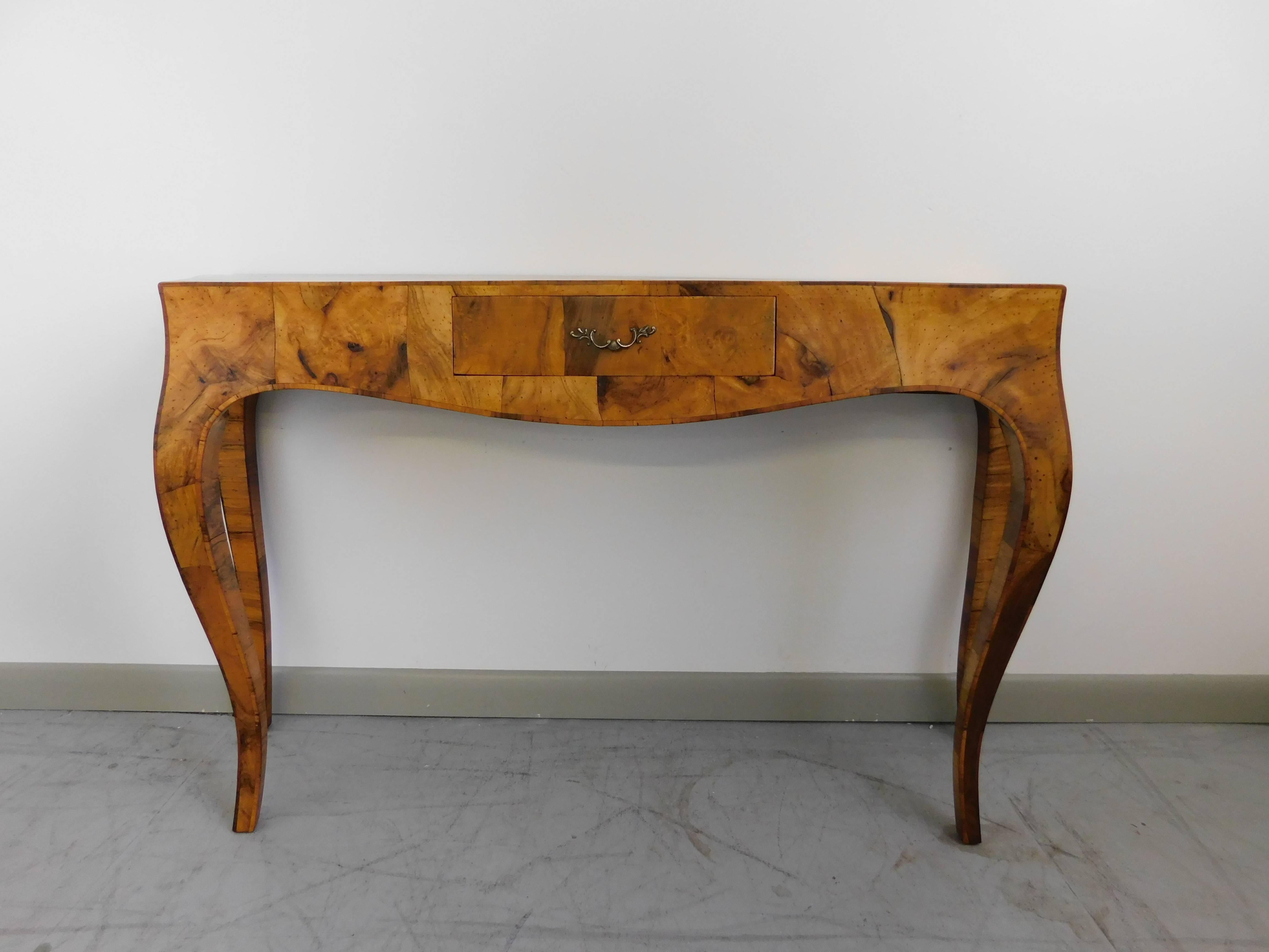 
Elegant Italian walnut oyster burl wood console table, circa 1950s. Cabriole legs to the front and rear with bombe front and sides. Finely cast brass filigreed pull and a single center drawer. Professionally refinished. 
