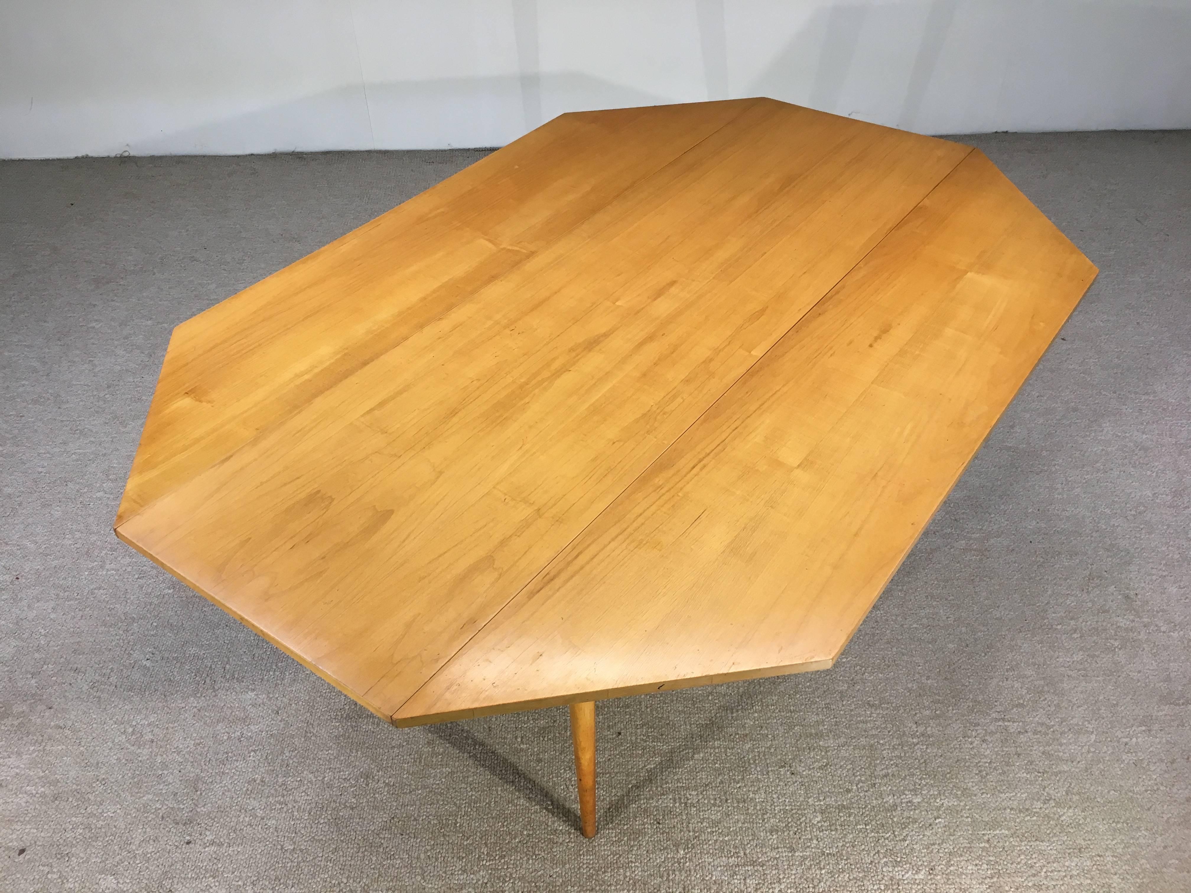 Beautiful maple drop-leaf dining table by Paul McCobb having resistance spring lock arms for stability and ease of adjustment. This unassuming table seats up to eight people when opened. It is a gorgeous design in it's finished maple and splayed