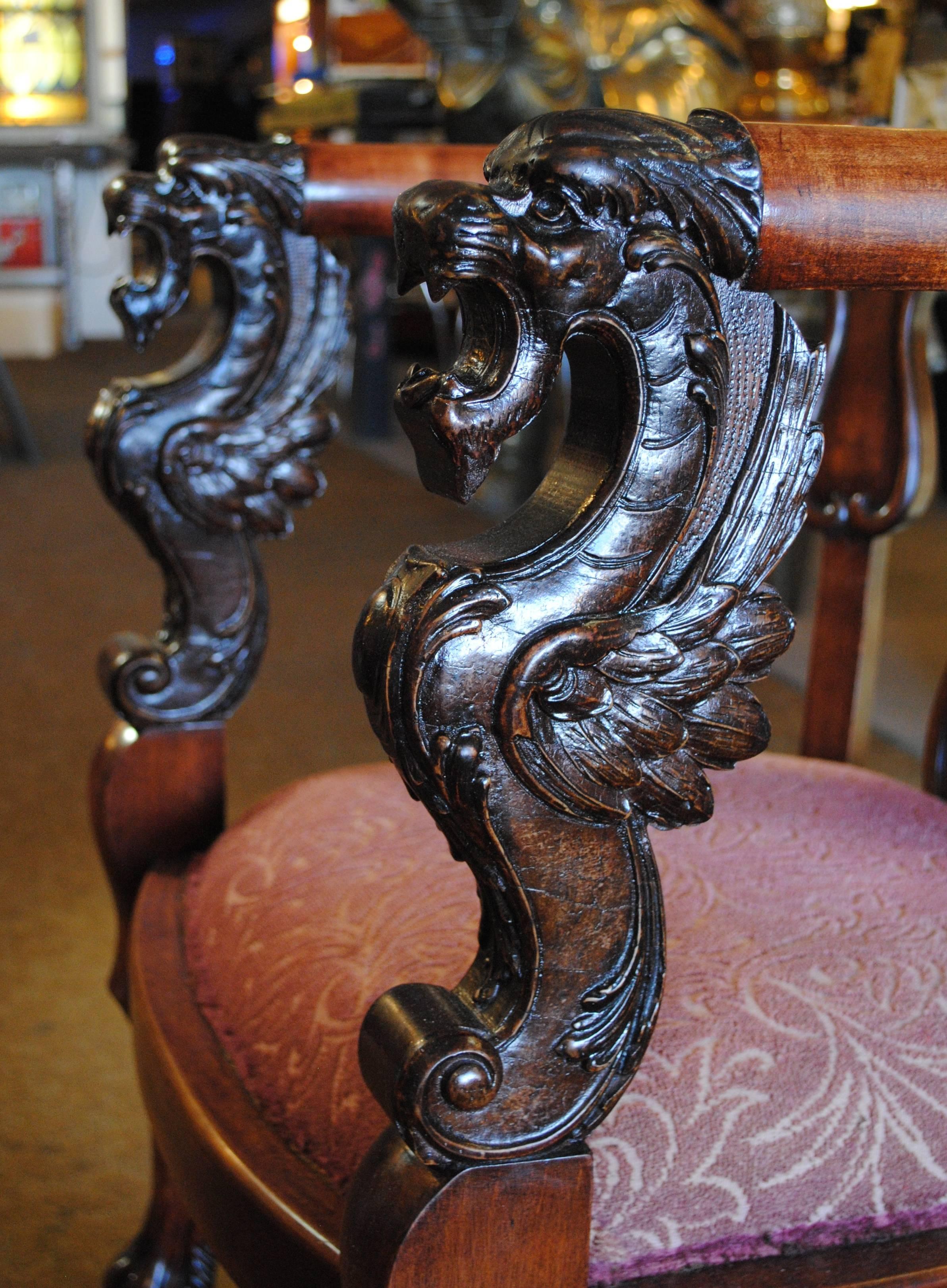 Antique wood rocking chair with carved griffins on the arms.