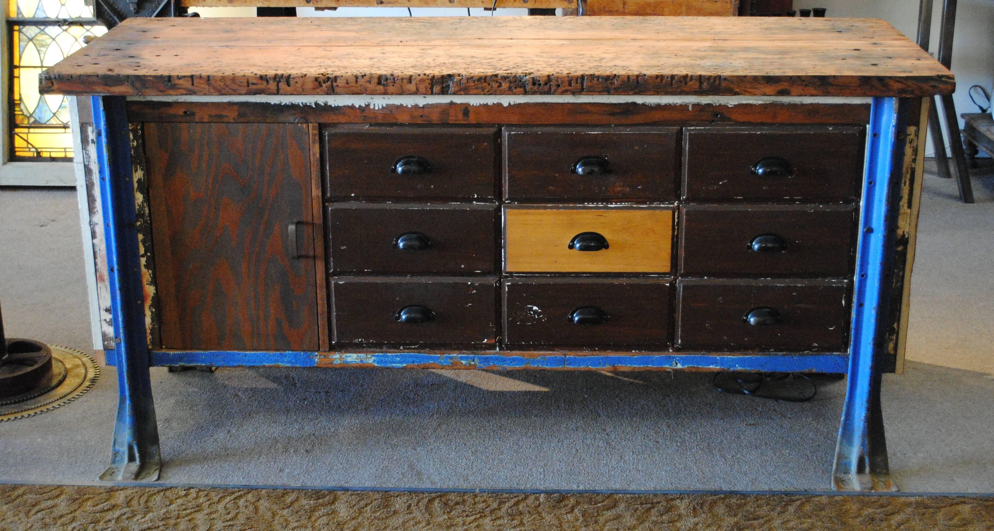 This Vintage workbench has the perfect amount of wear on the dark wood and blue steel legs. Versatility is key! This workbench is comprised of 9 drawers and one-door. This piece could be an entry table, kitchen island, craft storage.