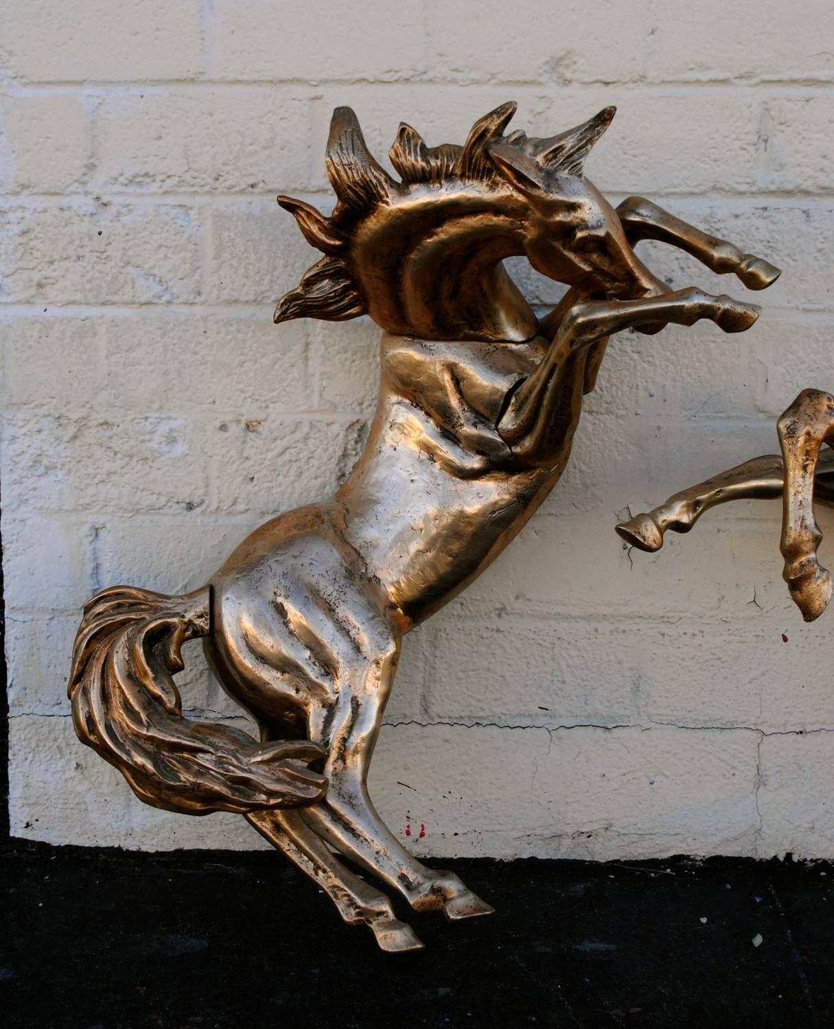 Pair of substantial metal Mid-Century Modern wall mount bucking horses. Color is more brass/gold than shown.