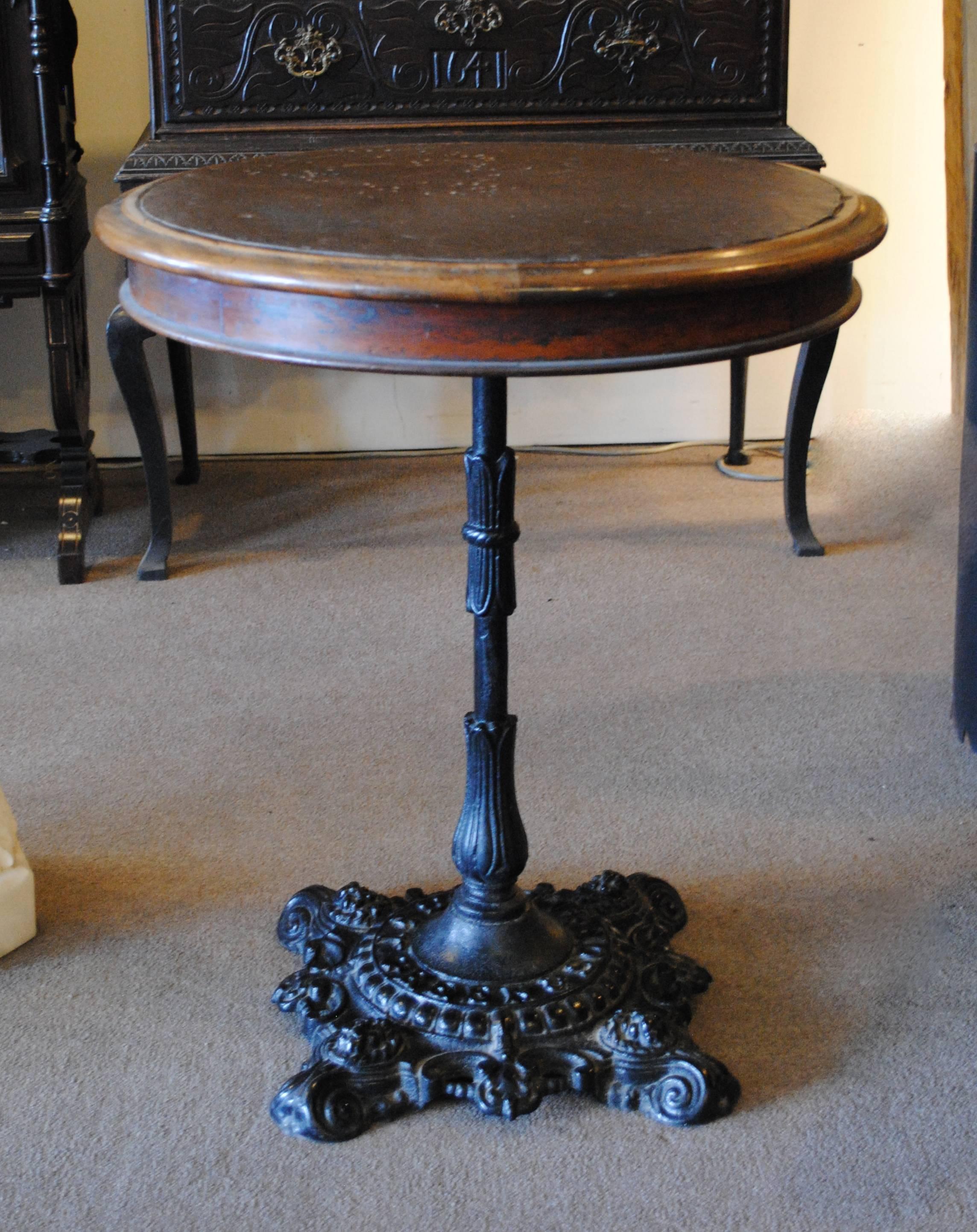 19th century English pub table made by T. Green & Sons, Leeds. Features original leather inset table top and cast iron base with lion face accents.