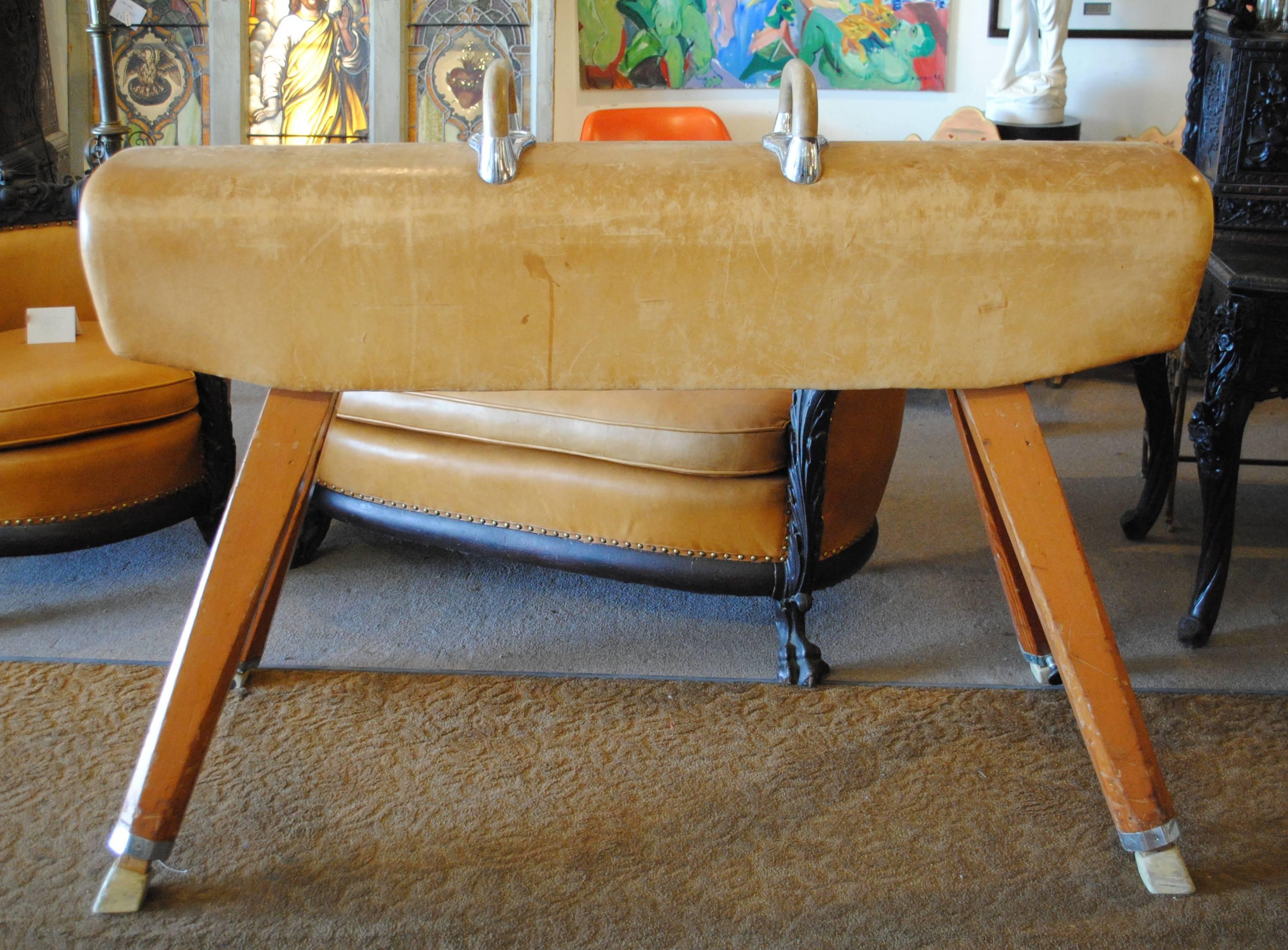 Vintage gym pommel horse with a worn leather surface, wood handles and wood legs. Measures: Pommel width 14