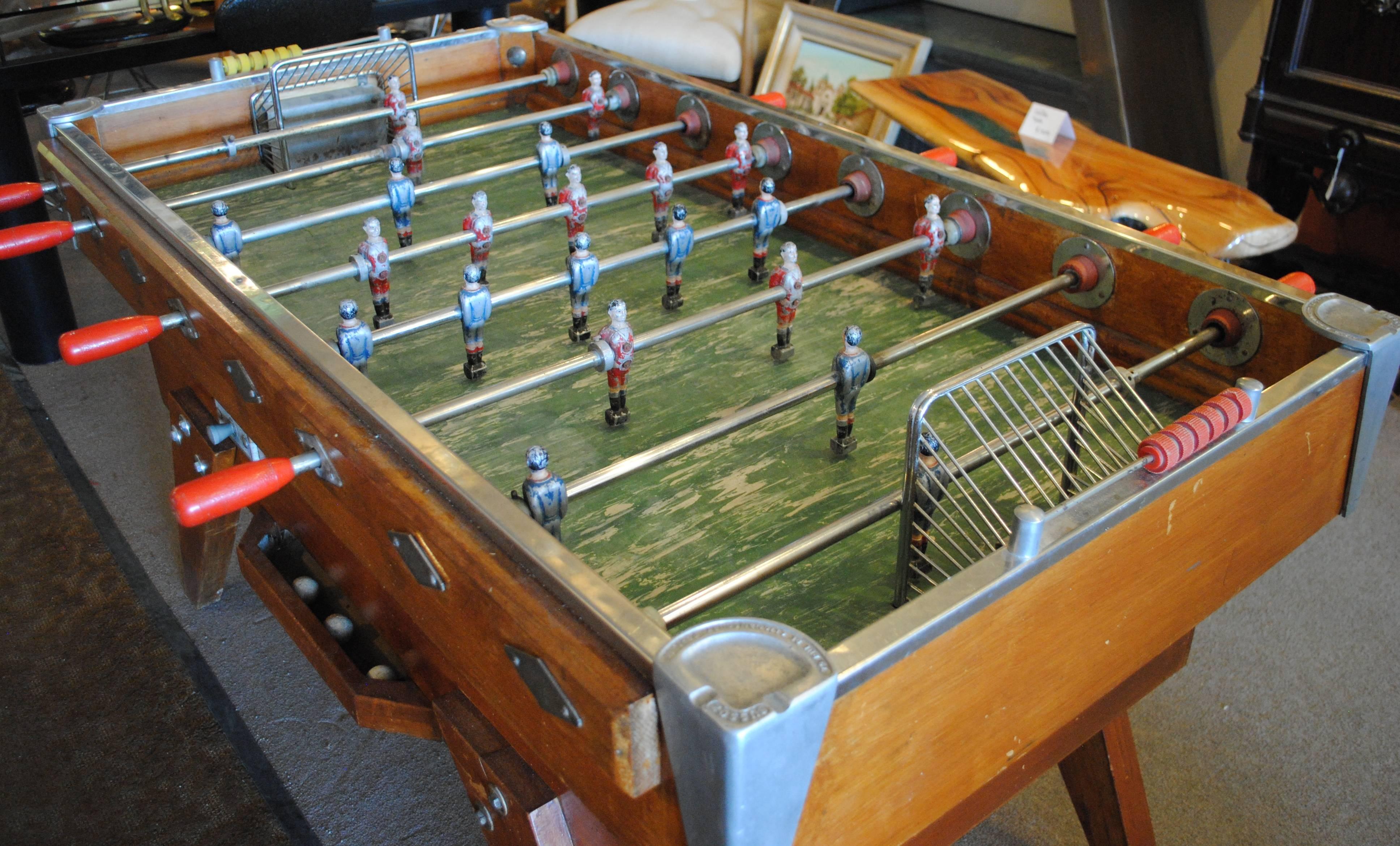 Vintage French foosball table by Bussoz. All players are solid cast metal, with original paint. The cabinet is all solid wood, displaying an honest patina of time. The corner supports are actually cast aluminium ashtrays, with the makers name and