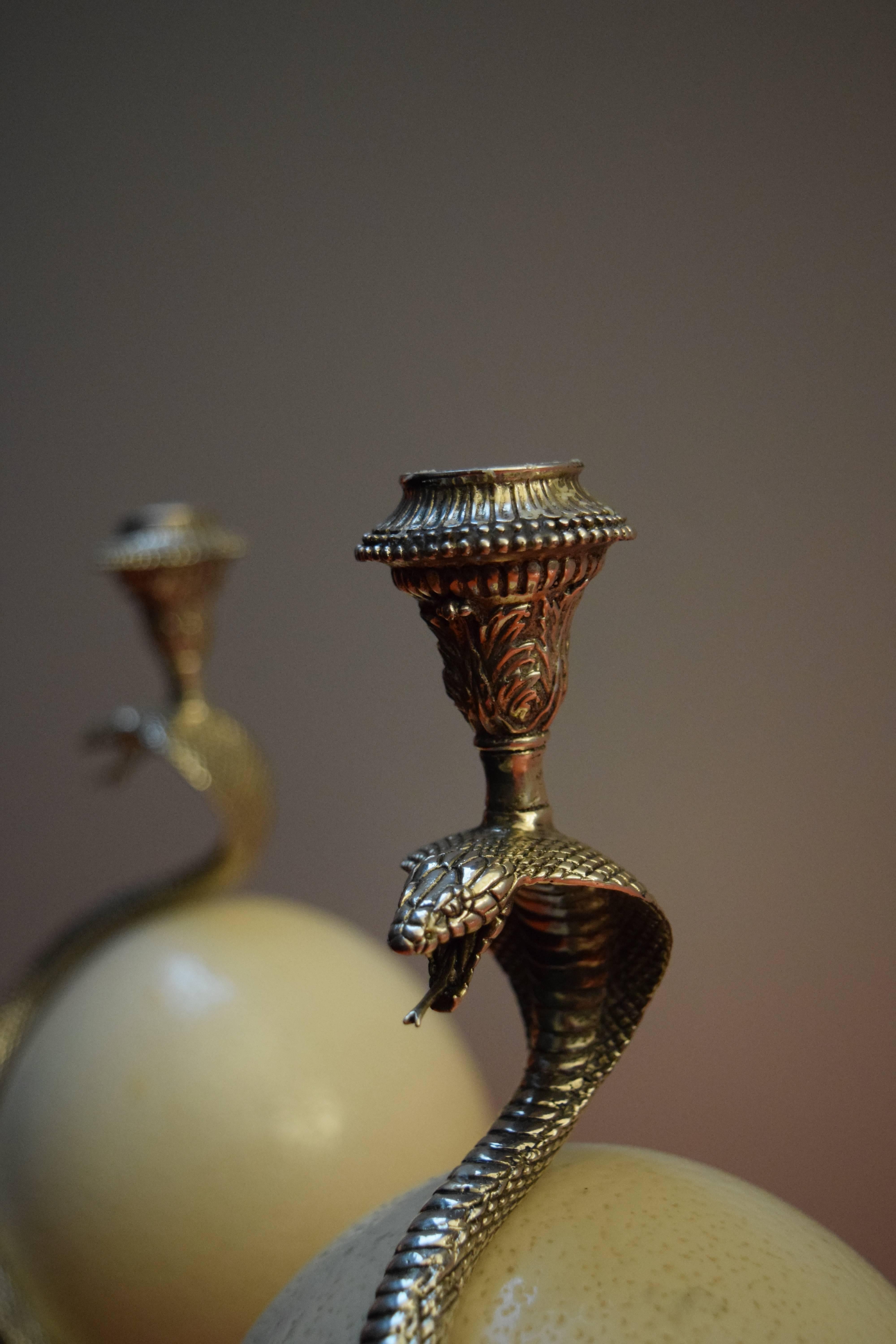 Exclusive candleholders, a silver cobra embracing an ostrich egg.