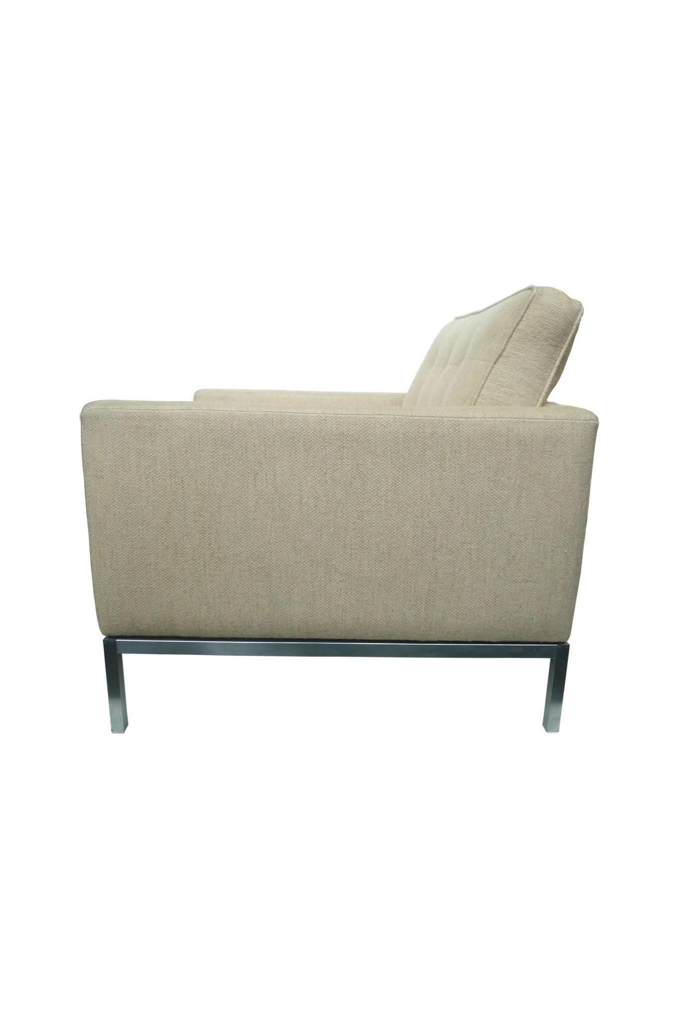 This Florence Knoll club chair maintains its original beige-cream upholstery. It is a fine example of Knoll's modernist designs: smooth, simple lines and planes in service of comfort. The chair's elegant features include tufted cushions framed by