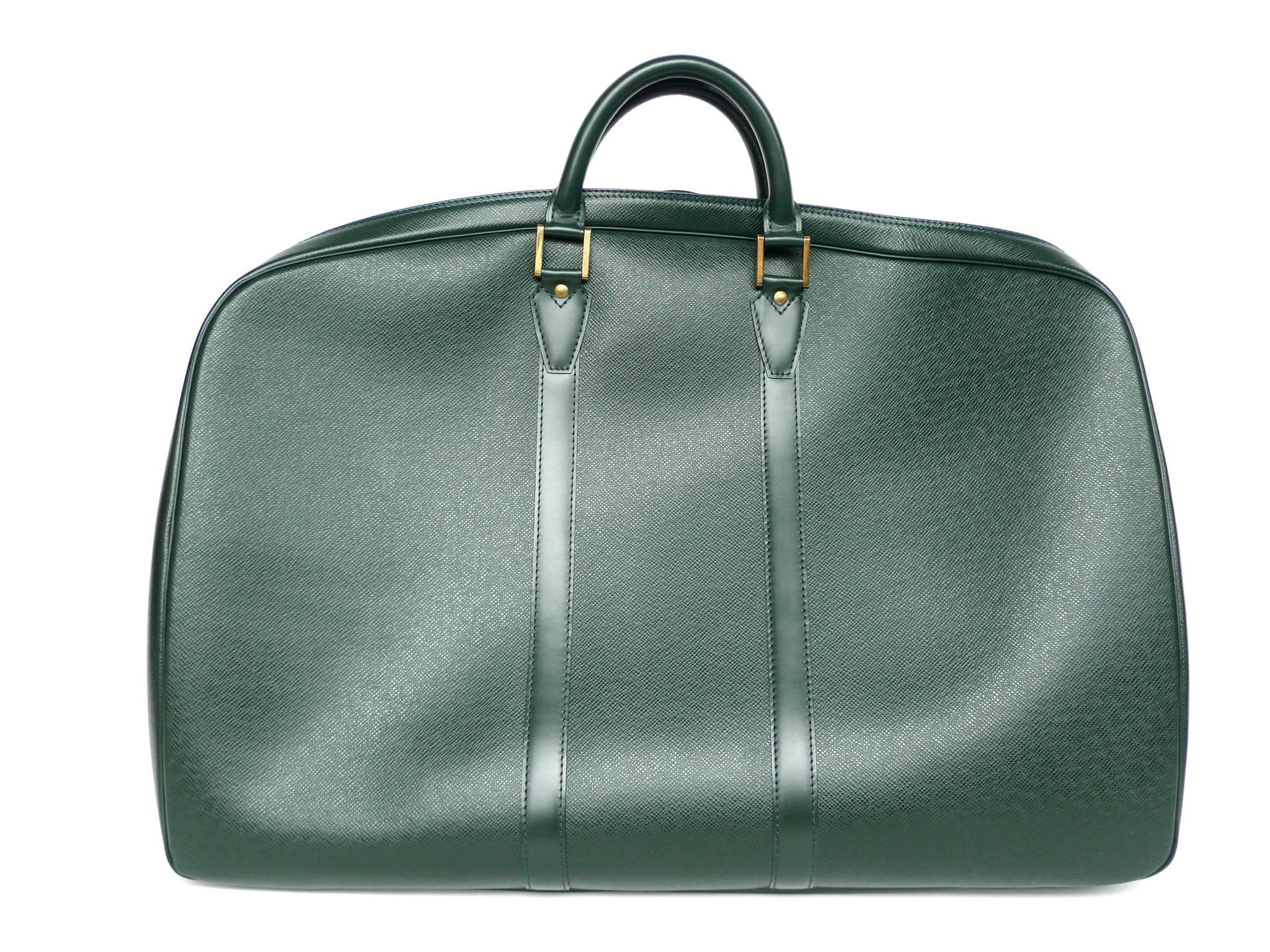 This Louis Vuitton Helanga travel bag is crafted from durable, soft Taiga leather in a rich hunter green color. Gold-toned brass zippers beautifully outline the sleek, compact shape. Its interior is done in a pewter-green suede fabric. This lining