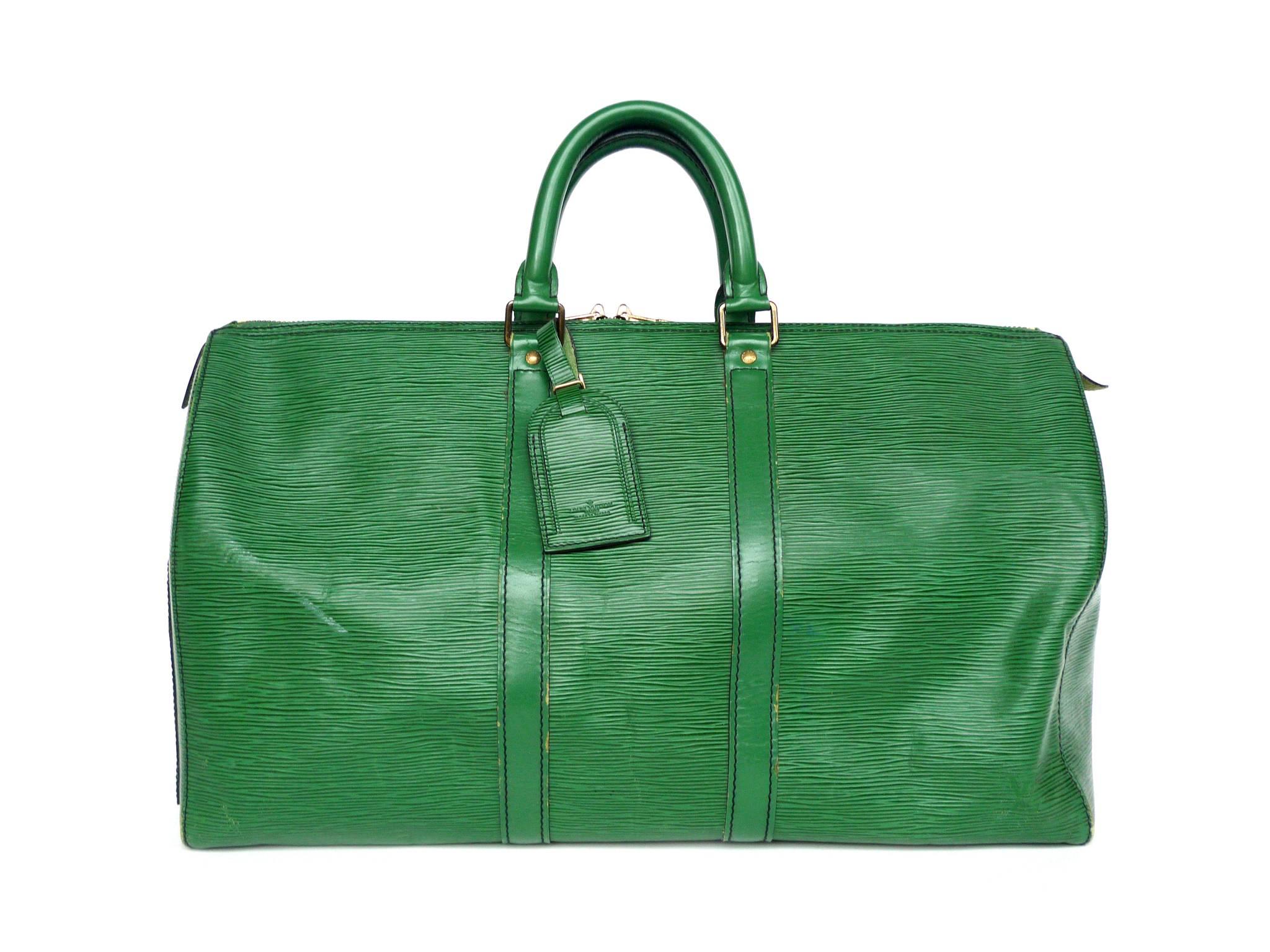 This Louis Vuitton Keepall 45 travel bag is crafted from durable, soft Epi leather dyed in an emerald green hue. Gold-toned brass hardware beautifully complement the sleek shape. The bag's interior is lined in a green suede fabric. Other functional