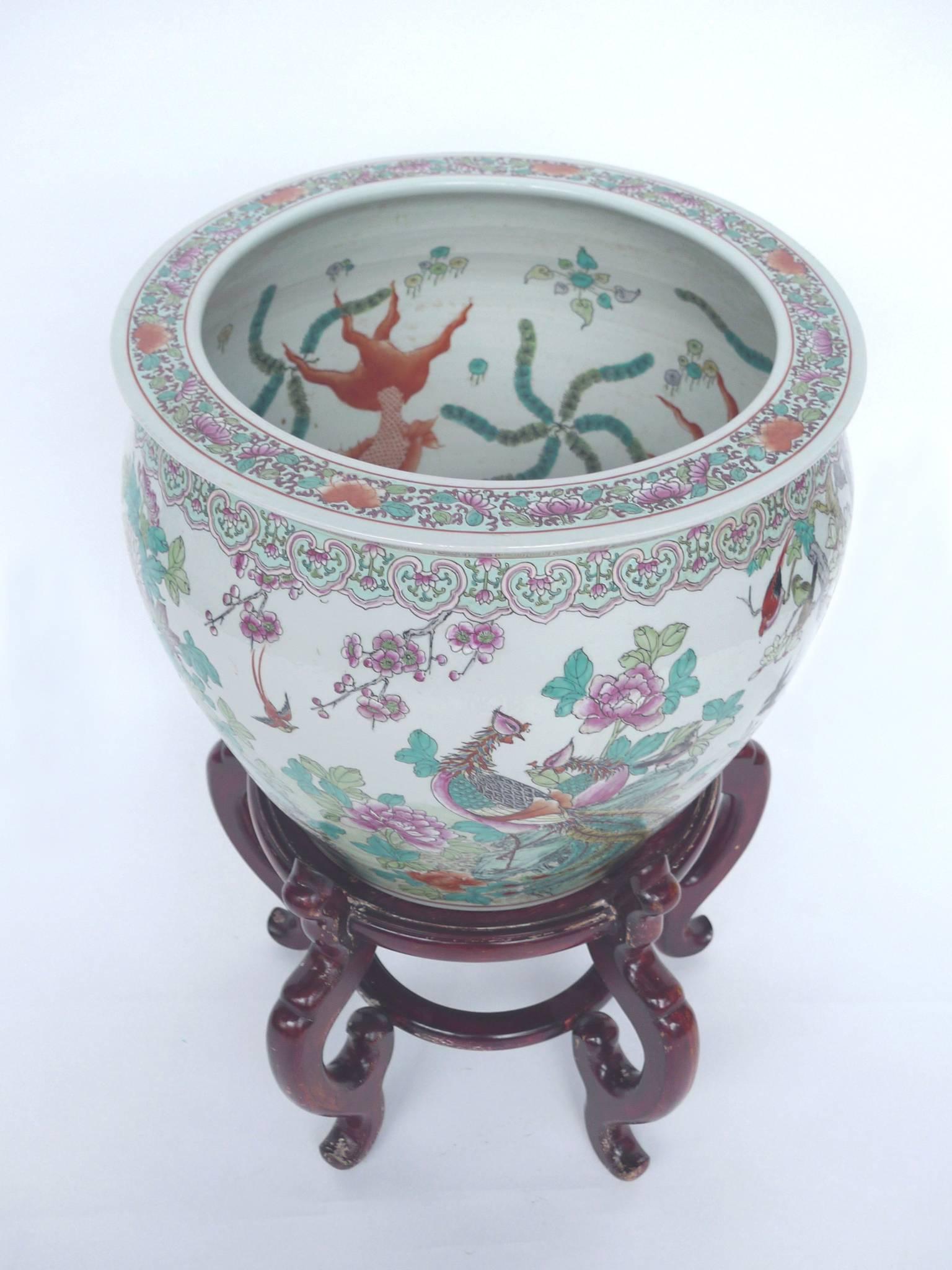 This white ceramic fishbowl is beautifully hand-painted. The exterior design depicts colorful birds and flowers rendered in soft washes and finely drawn contours, while the interior's design is of goldfish and plant flora. The bowl is accompanied by