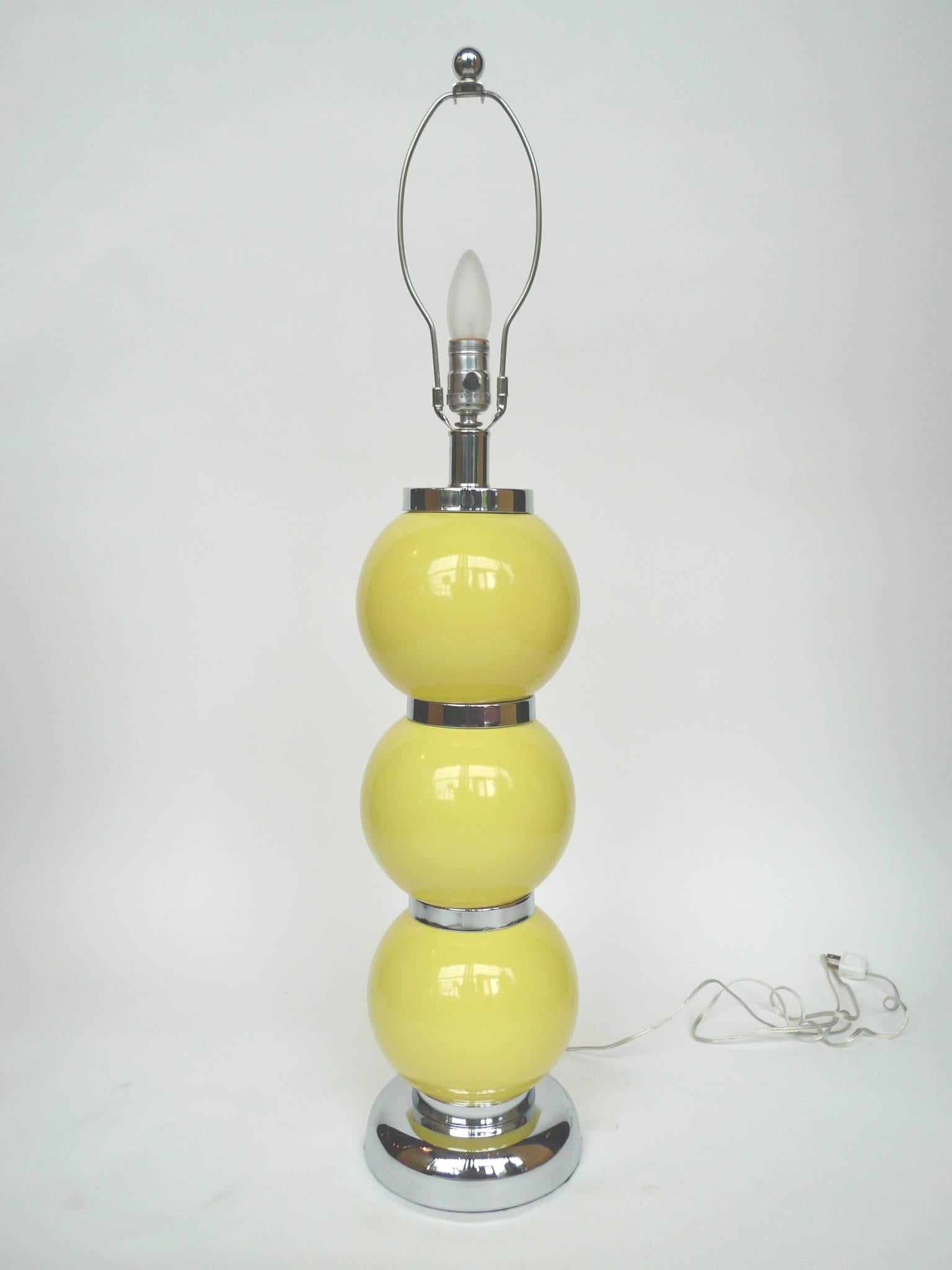 These striking lemon-yellow lamps are in a similar style to the stacked ball table lamps designed by George Kovacs. The spheres are glazed ceramic while the base and the segments between the spheres are chrome. These lamps are newly rewired and
