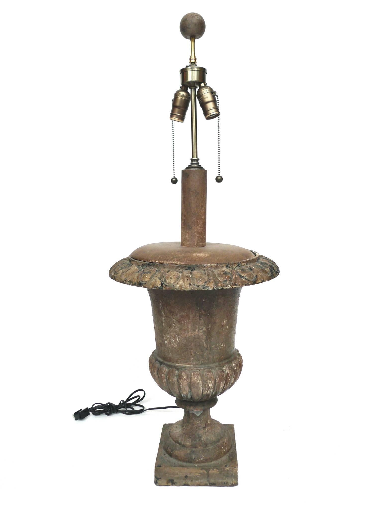 These lamps are crafted from cast iron garden urns dating back to the early 20th century. Their style is reminiscent of neoclassical designs. The patina that has developed further gives a sense of antiquity. The weathered tone and textures are