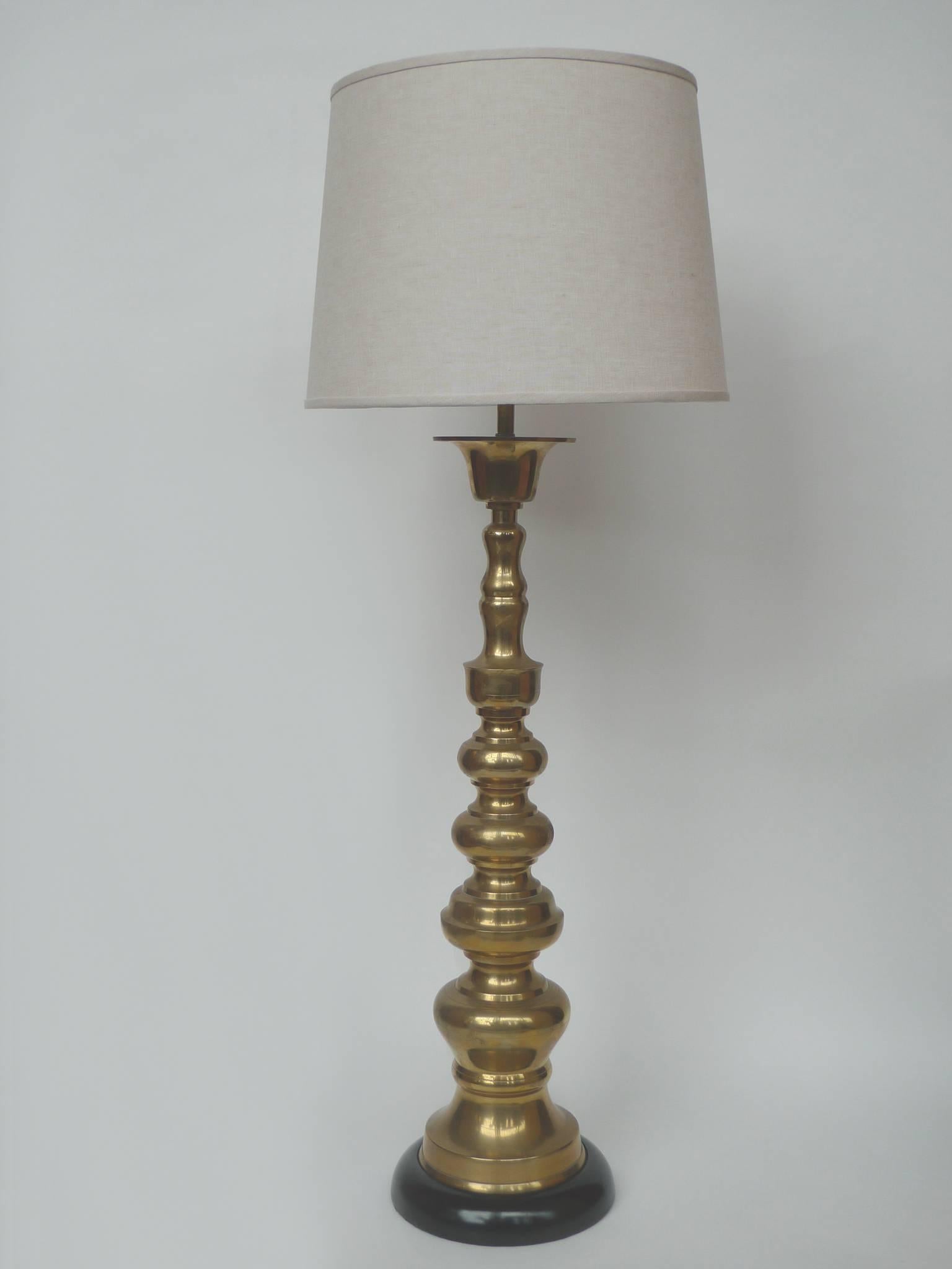 These table lamps by Stiffel beautifully illuminate. They are striking for their height and baluster forms in polished brass. The lamps are newly rewired with new brass hardware and new silk shades. The bases are round wood painted in glossy black.