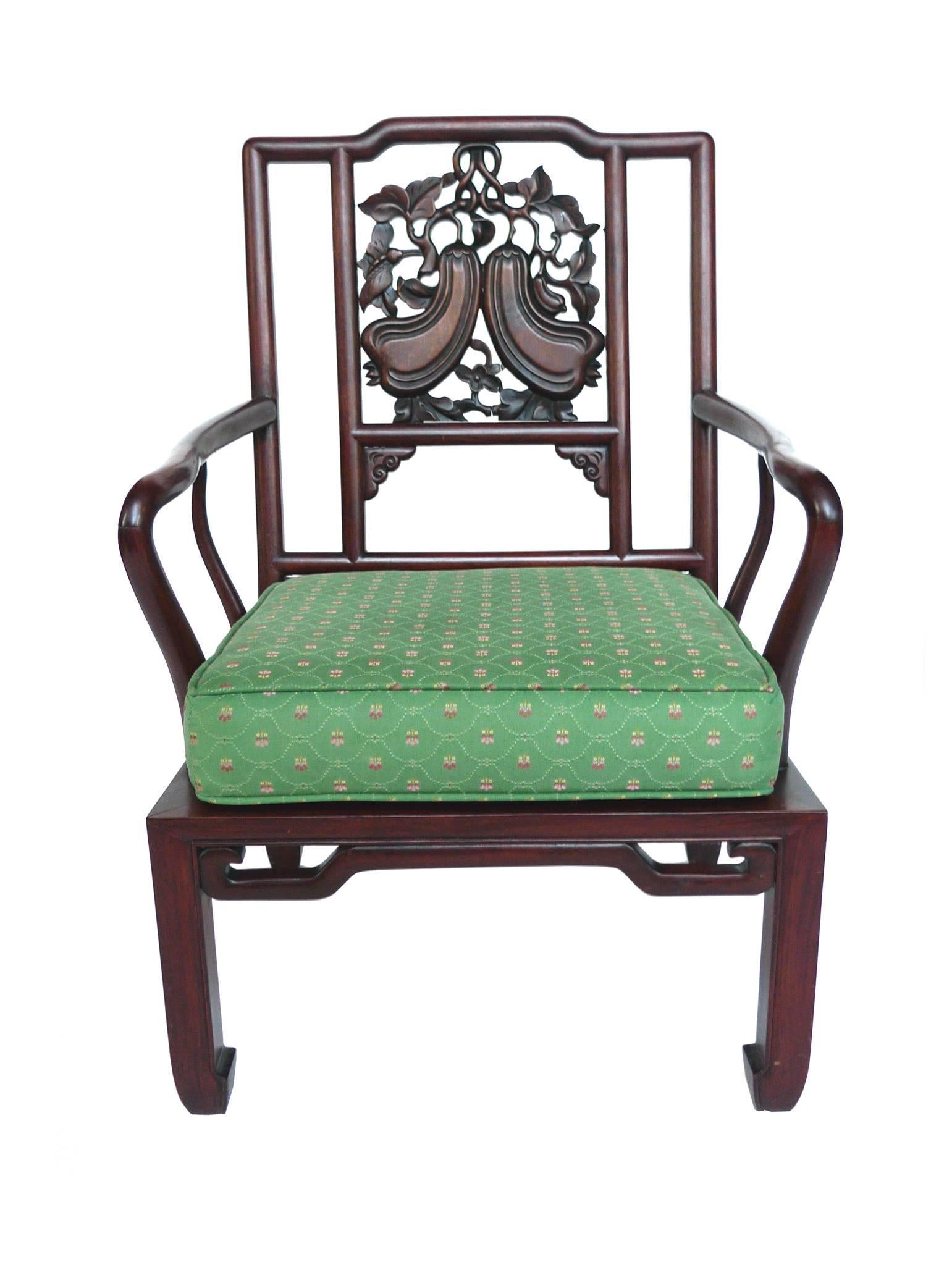These Chinese armchairs consist of rosewood. The wood is a warm reddish brown. It's beautifully carved with slender, curved arms and a low, geometric seat. The back's design features carved gourds, a symbol of good fortune. The seat cushion is a