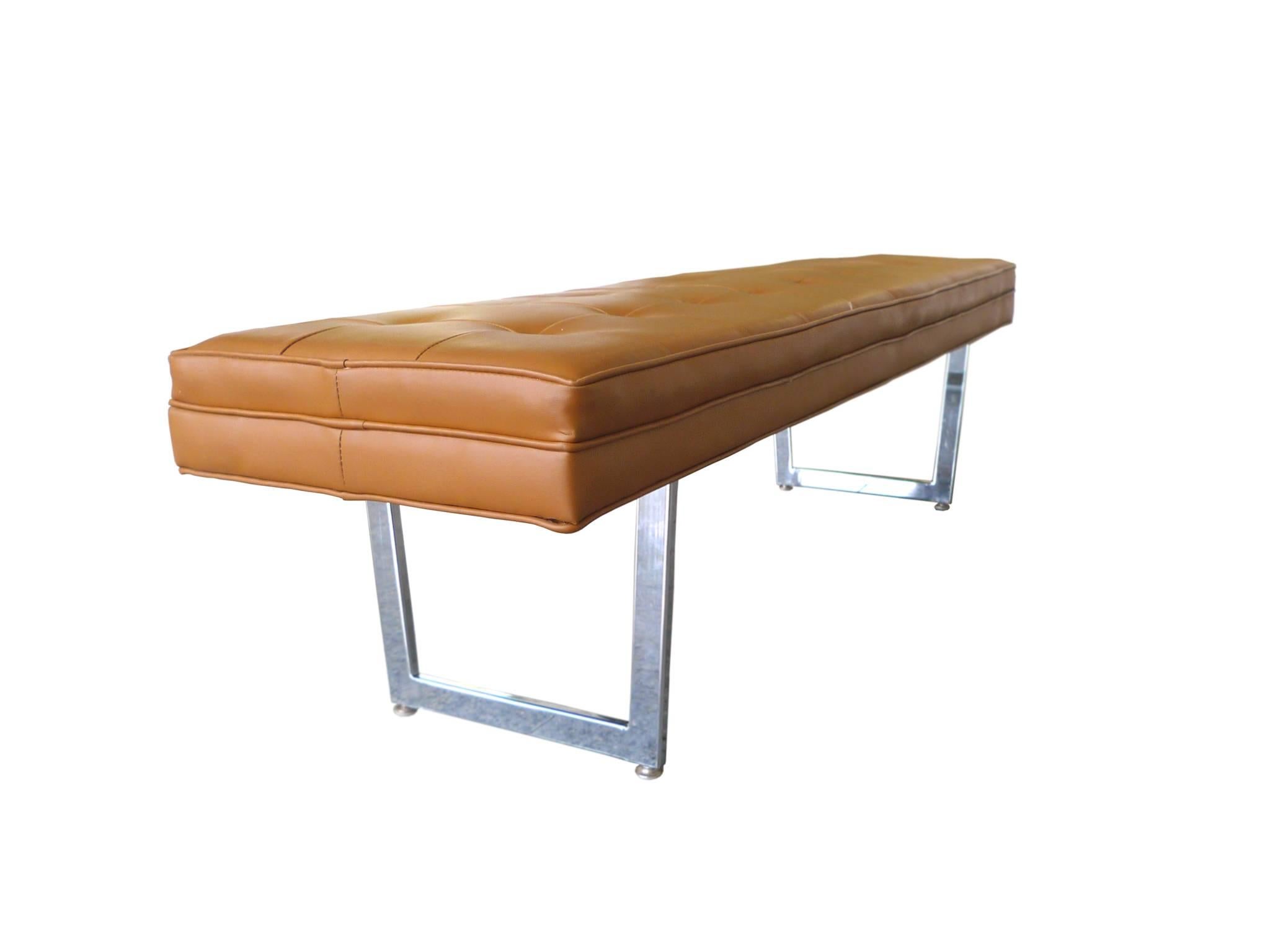 This minimally designs Knoll-style bench was manufactured by the Patrician Furniture Company in the 1970s. The upholstery is vinyl in a rich caramel hue with biscuit tufting and piping. The sled legs are chrome bars with peg supports.