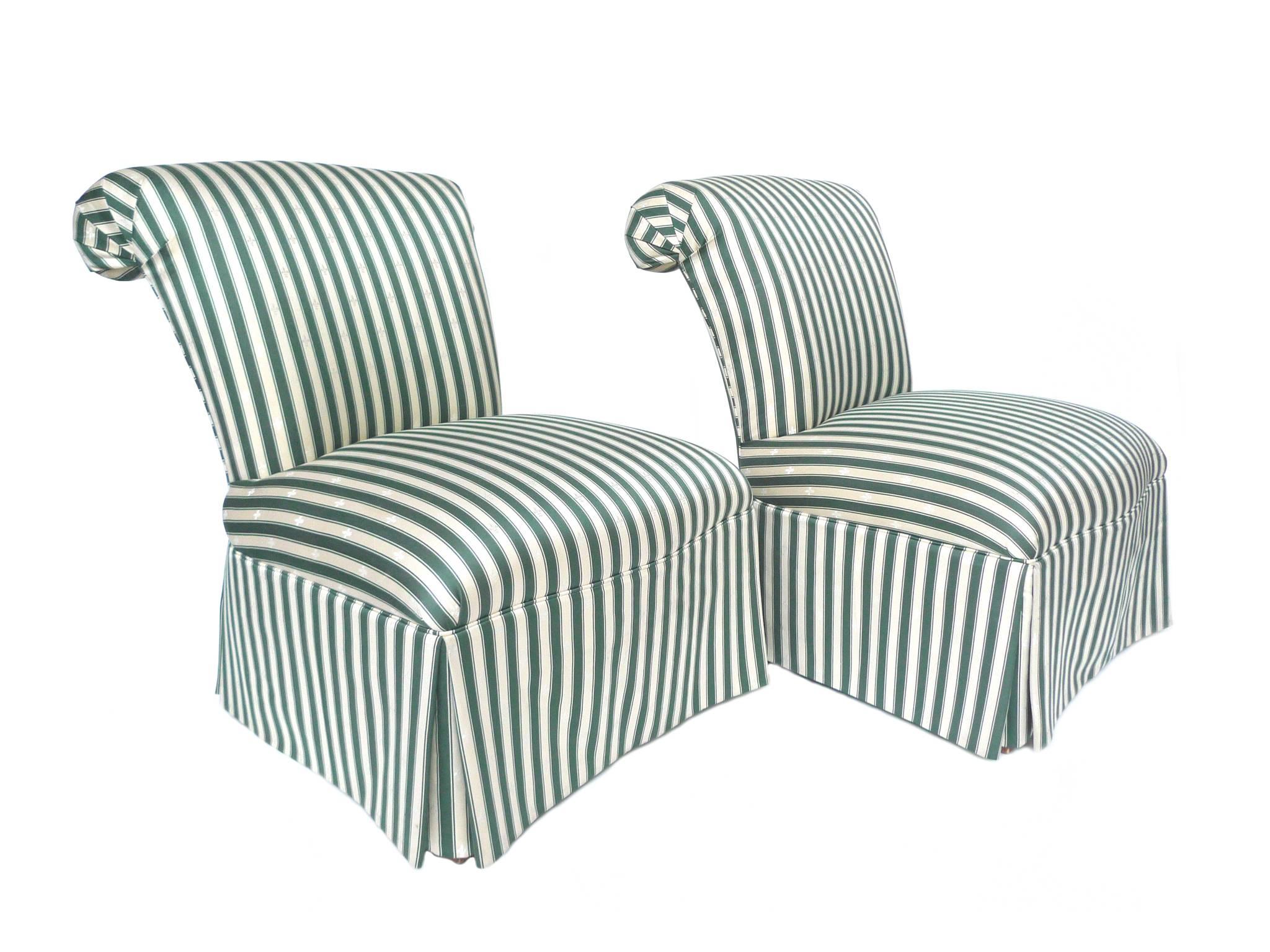 This pair of slipper chairs was manufactured by Henredon as part of their Schoonbeck Collection. The chairs are upholstered in a striped silk, in a green-and-champagne palette with embroidered fleur-de-lis patterning. Other design details include a