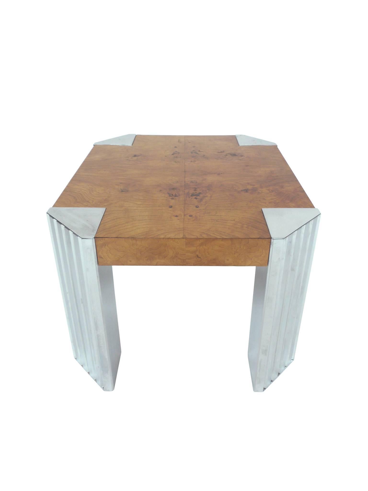 This 1970s cocktail table is in the Art Deco style. It's comprised of a 2 3/4-inch burl wood top and chrome legs. The tabletop is a rich honey yellow hue with a beautiful burl wood grain pattern, while the chrome legs are triangular with ridged