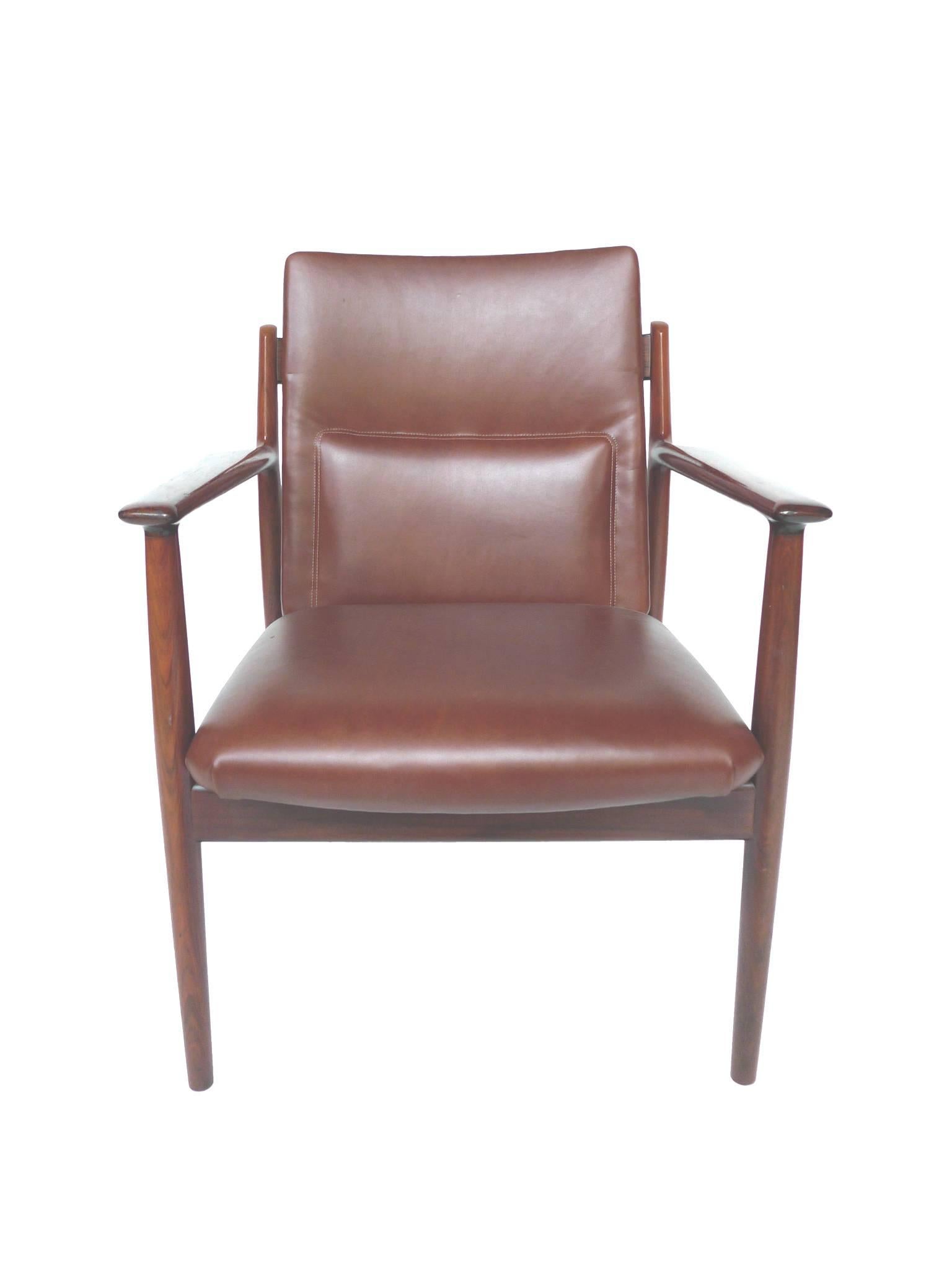 These Danish rosewood armchairs were designed by Arne Vodder and manufactured by Sibast Furniture. They are refinished and reupholstered in a maroon vinyl to match the deep red-brown of the rosewood. Vodder's design is one of clean lines. The chairs