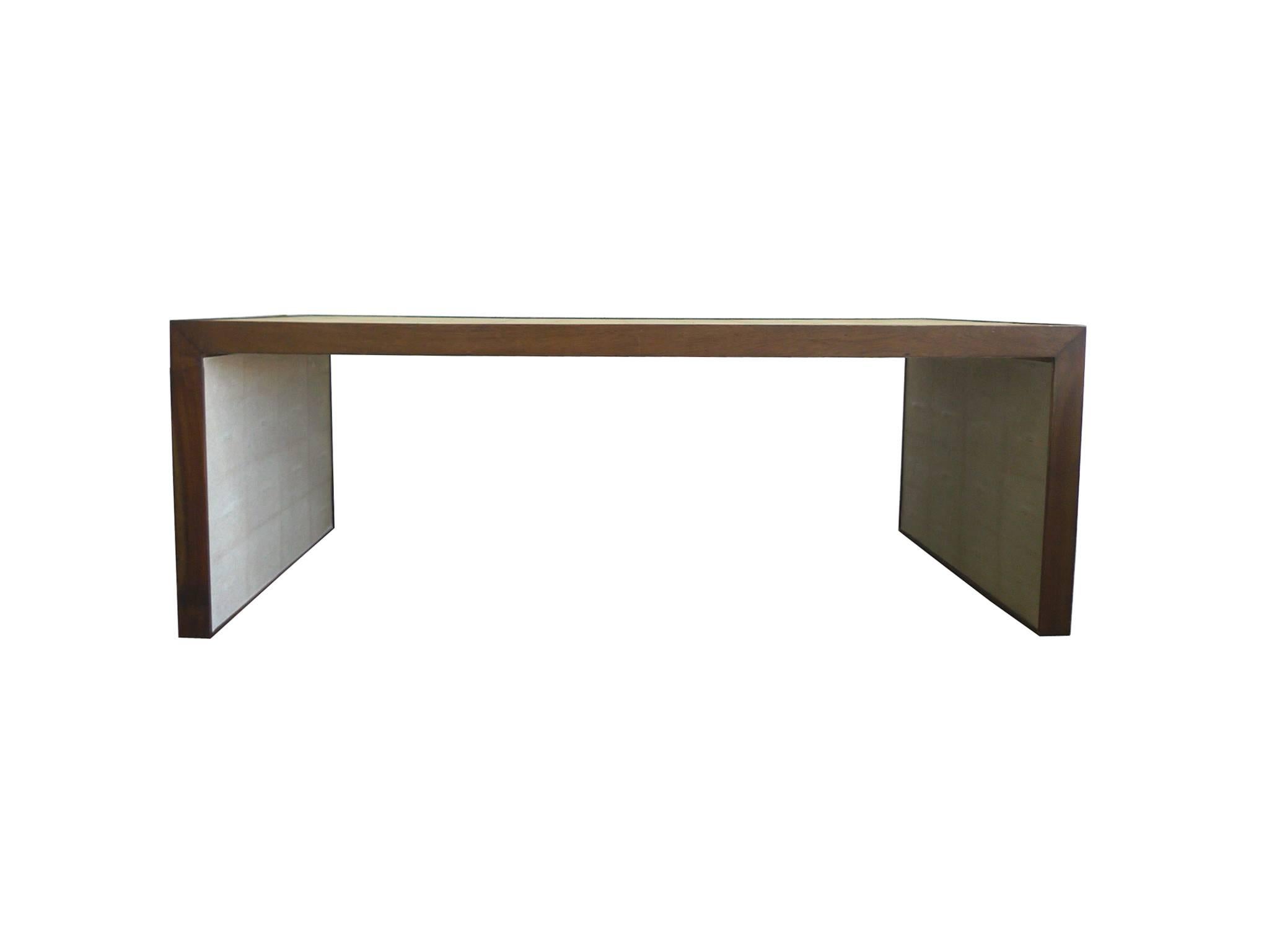 This set of nesting tables is comprised of one rectangular coffee table and a pair of smaller, square side tables. The frame is walnut wrapped in a beige, tactile shagreen. The walnut is visible on the sides as an elegant brown border.

Each side