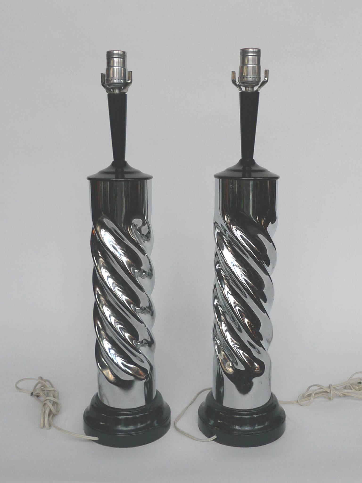 These table lamps are comprised of turned chrome bodies and black, enameled wood tops and bases. They are newly rewired and paired with new shades. The lamps are a dazzle with their reflective surfaces and throw light beautifully. They'll shine in