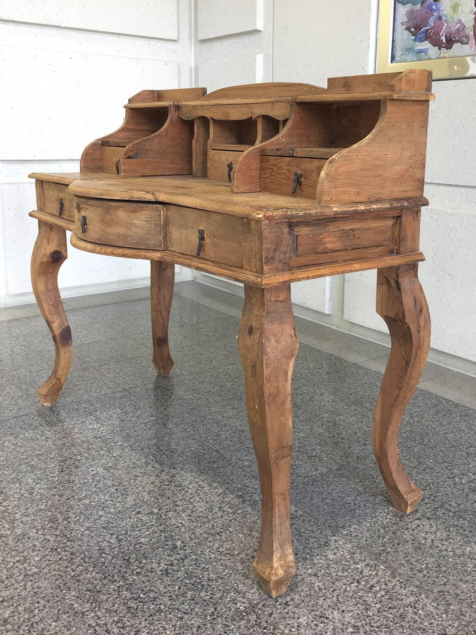 This 20th century French country desk is carved from pine wood. Its design is striking for its bare surface and stark lines. The cabriole legs, standing at 26 inches in height, beautifully lift the desktop; with their beautiful curves, the legs