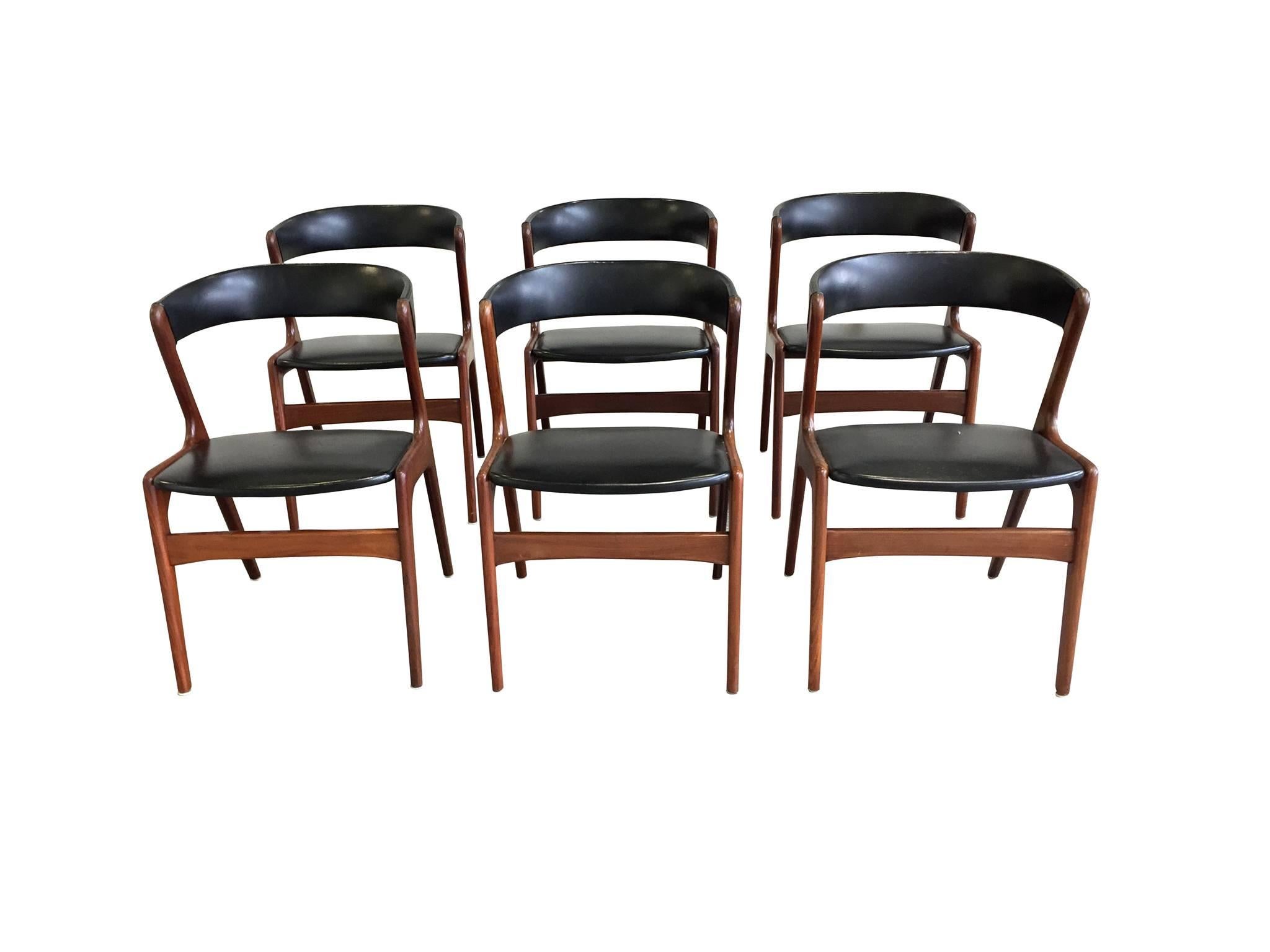 These six Danish modern side chairs were designed and manufactured by Omann Jun, circa 1950s-1960s. They are comprised of teak frames in a dark finish and black skai upholstery. This minimal combination of bold colors is really beautiful. It