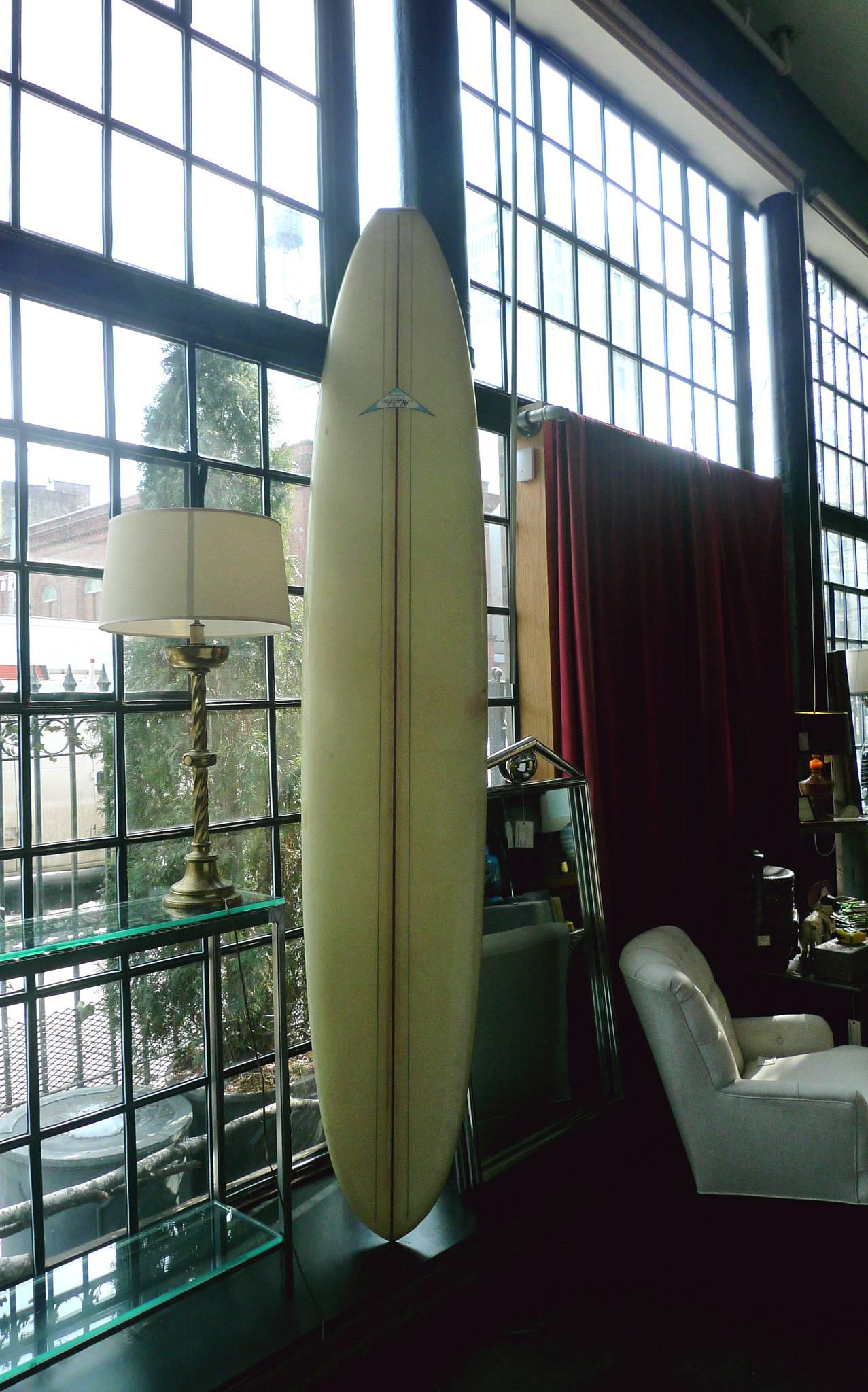 This vintage 1960s Malibu Competition longboard has a beautiful pale yellow glaze. A burgundy stripe runs along its centre. It's perfect for the surfboard connoisseur or the nautical-minded collector. 

Measures: 4