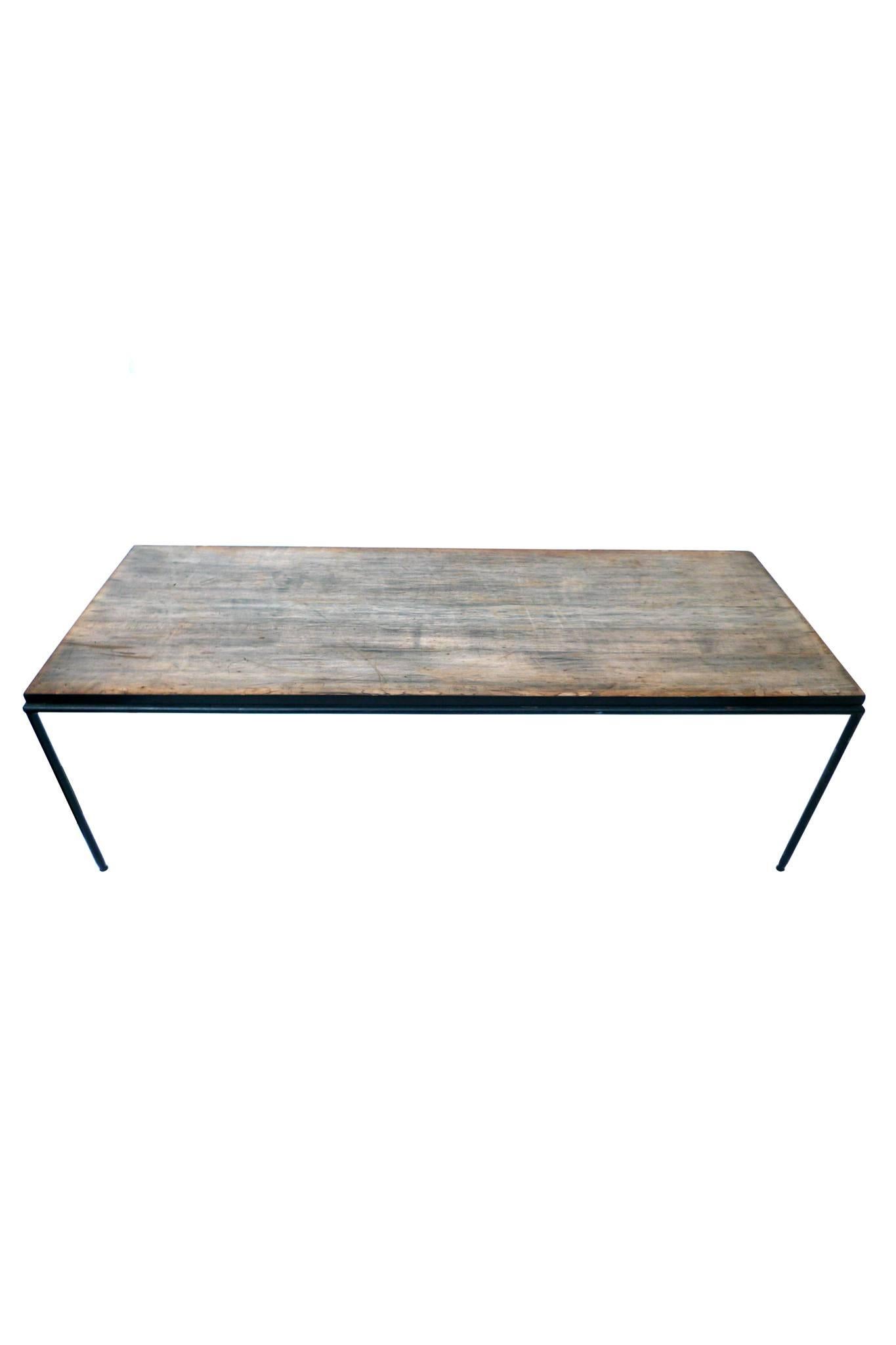 This midcentury table by Paul McCobb consists of a burnished teak table top and wrought iron frame and legs. The teak top has a very rich distressed look. It's smooth and beautifully aged. The sides are painted black, as are the wrought iron frame