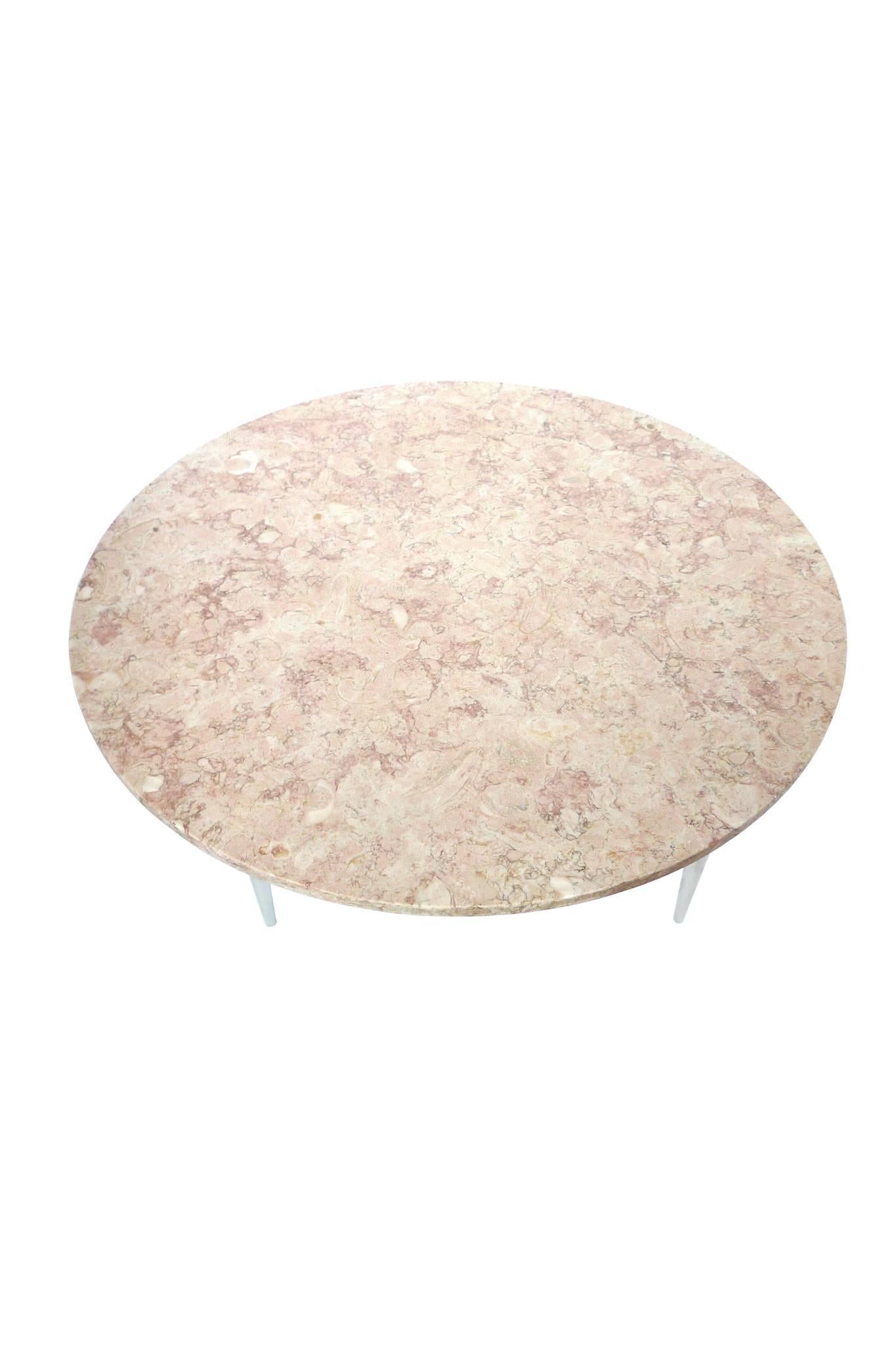 This round cocktail table is an Heirloom Quality Weiman table. Its top is travertine with a beautiful rosy pattern verging on the floral. The base is a wood with newly chromed legs that taper downward. It's a striking piece that will anchor your