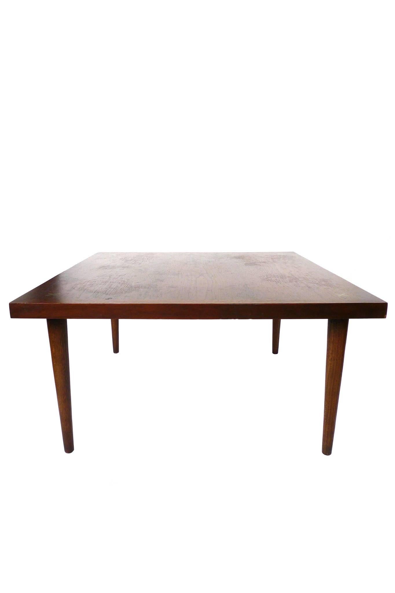 This cocktail table was designed by Merton Gershun for American of Martinsville. It is walnut with a rich dark finish. Brass x-inlays adorn the tabletop, one at each corner. while the legs are high and taper downward. This is an elegant cocktail