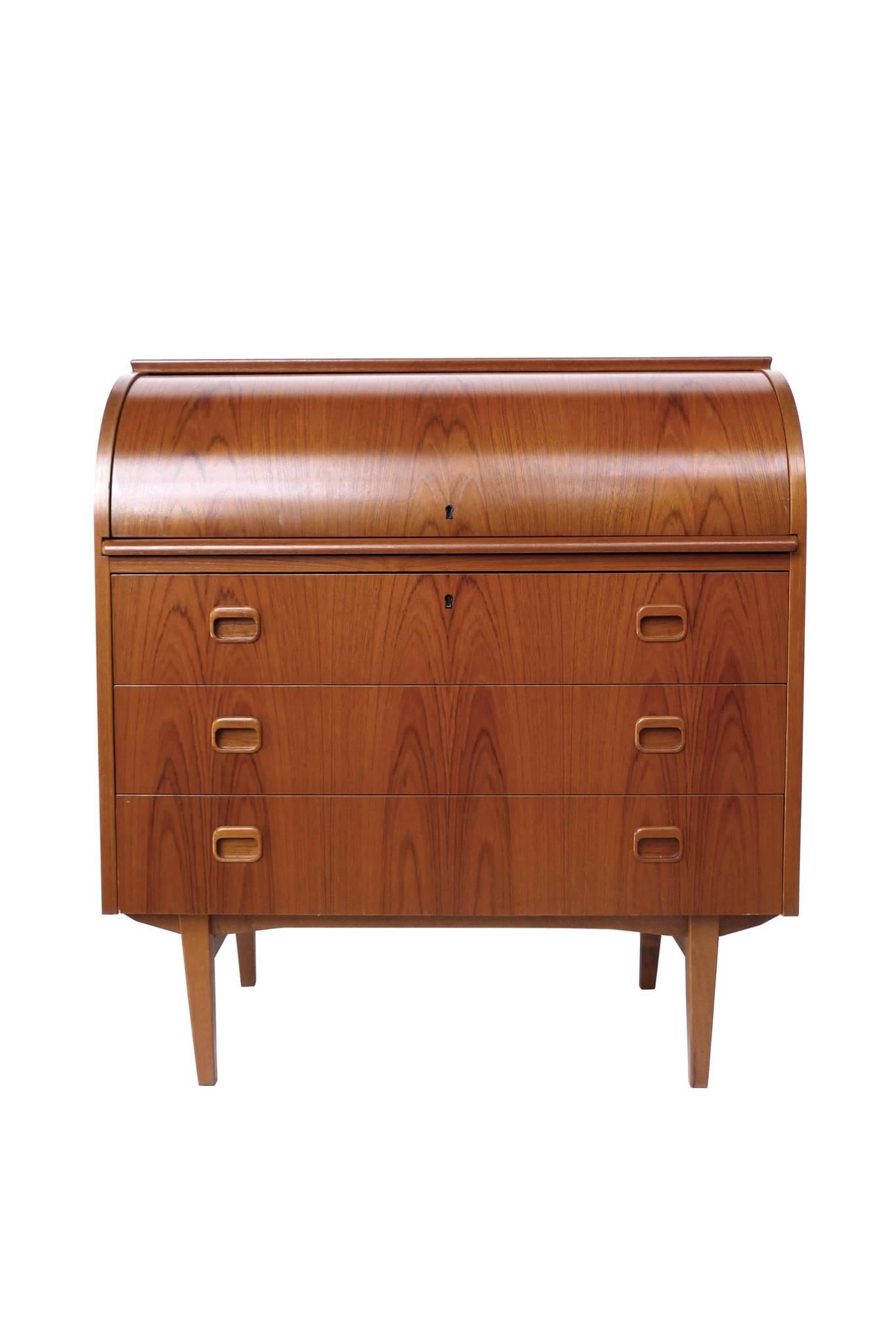 This Mid-Century Modern roll-top secretary desk is Danish design. It's crafted from rosewood and is comprised of a secretary desktop and a chest of drawers. There are three drawers for ample storage, which includes a functioning key. The roll-top