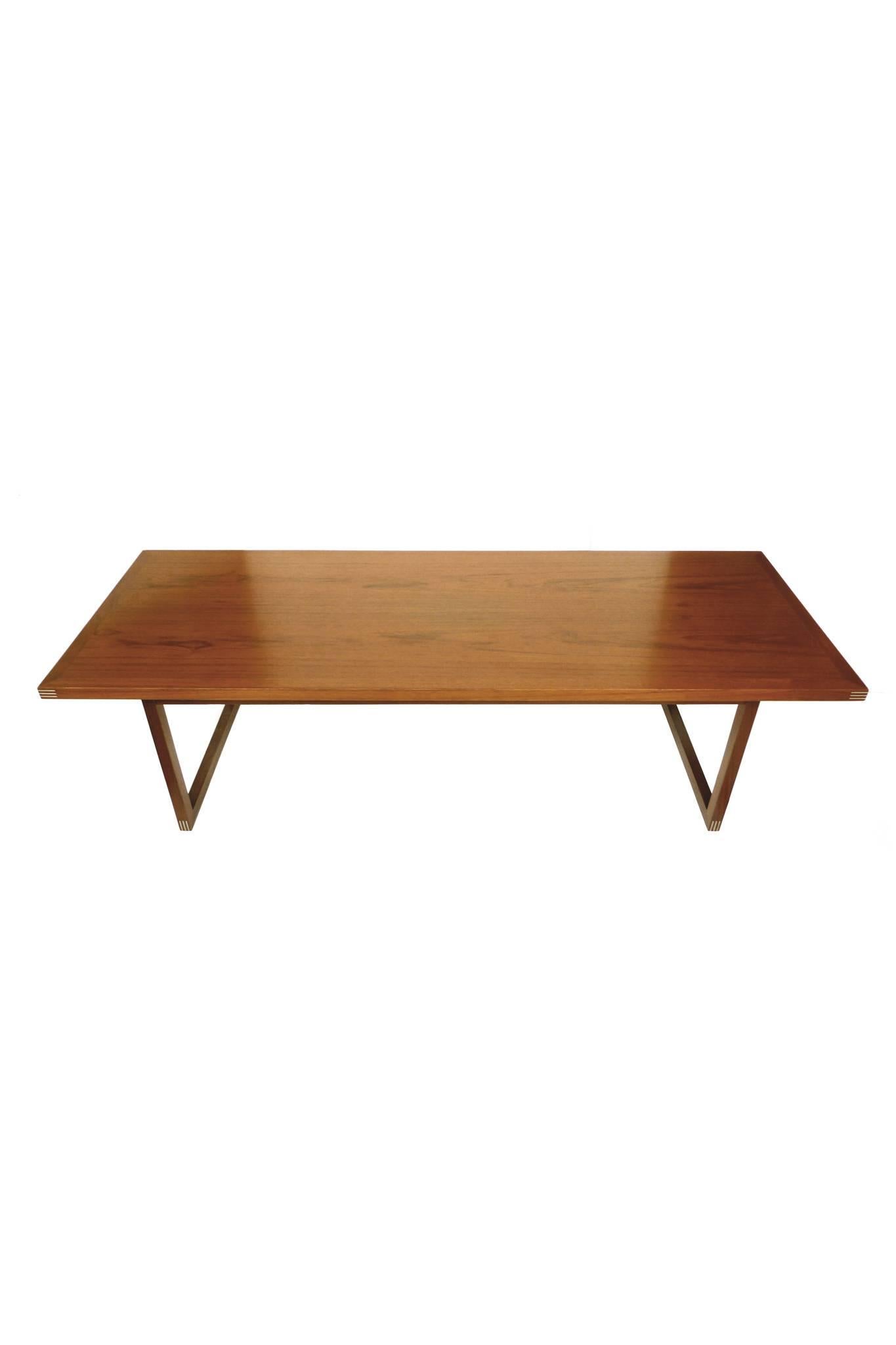 This Danish teak coffee table is designed by Rud Thygesen for Heltborg Møbler. It consists of a one inch-thick top beautifully supported by streamlined sleigh legs. This dynamic design is complemented by metal inlays that adorn the edges. The table